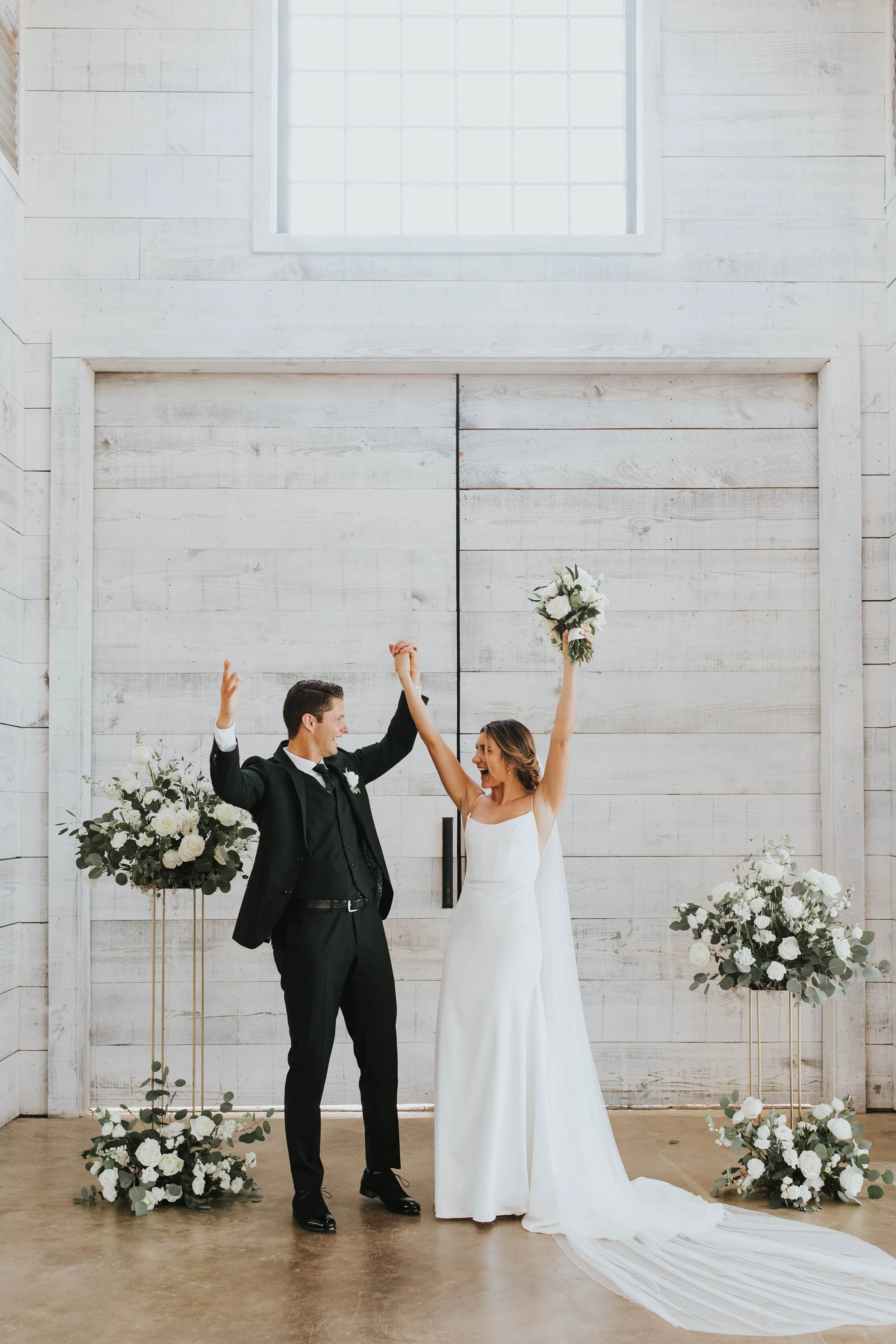 Newly married couple with hands in the air at an indoor ceremony at Two Wishes Ranch