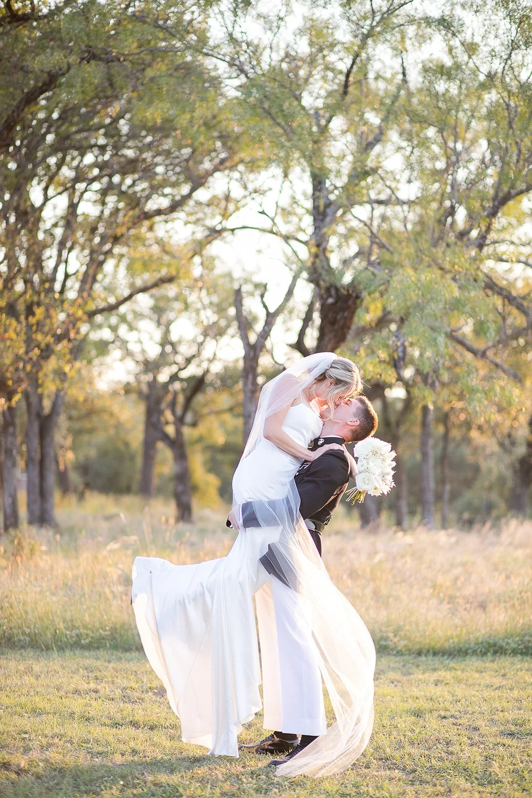 Couple kissing in a field at sunset and groom in his military uniform in the Hill Country