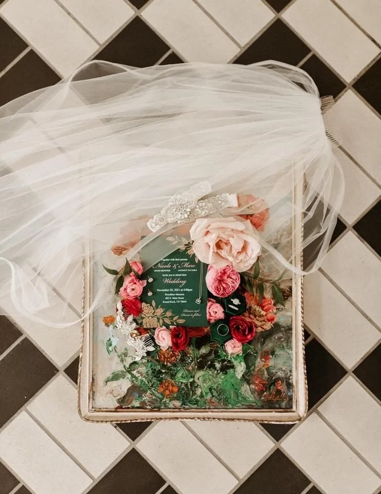 Glass box with wedding details and bridal veil on a black and white floor at Woodbine Mansion in Round Rock Texas