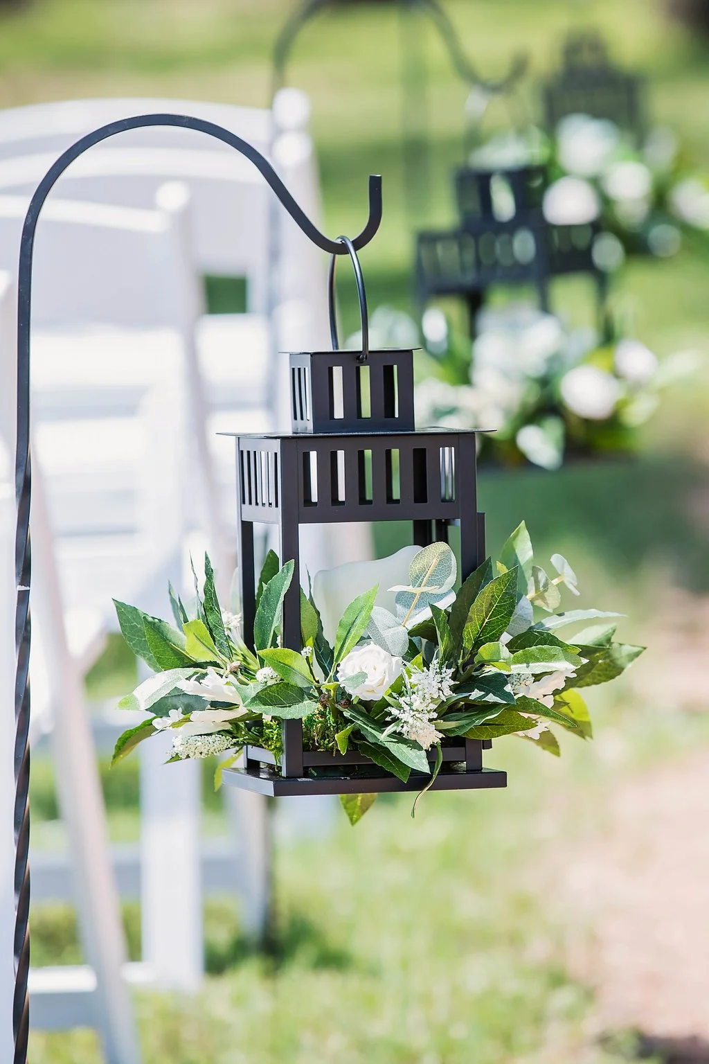 Black lantern on a Sheppard hook at a wedding ceremony isle marker