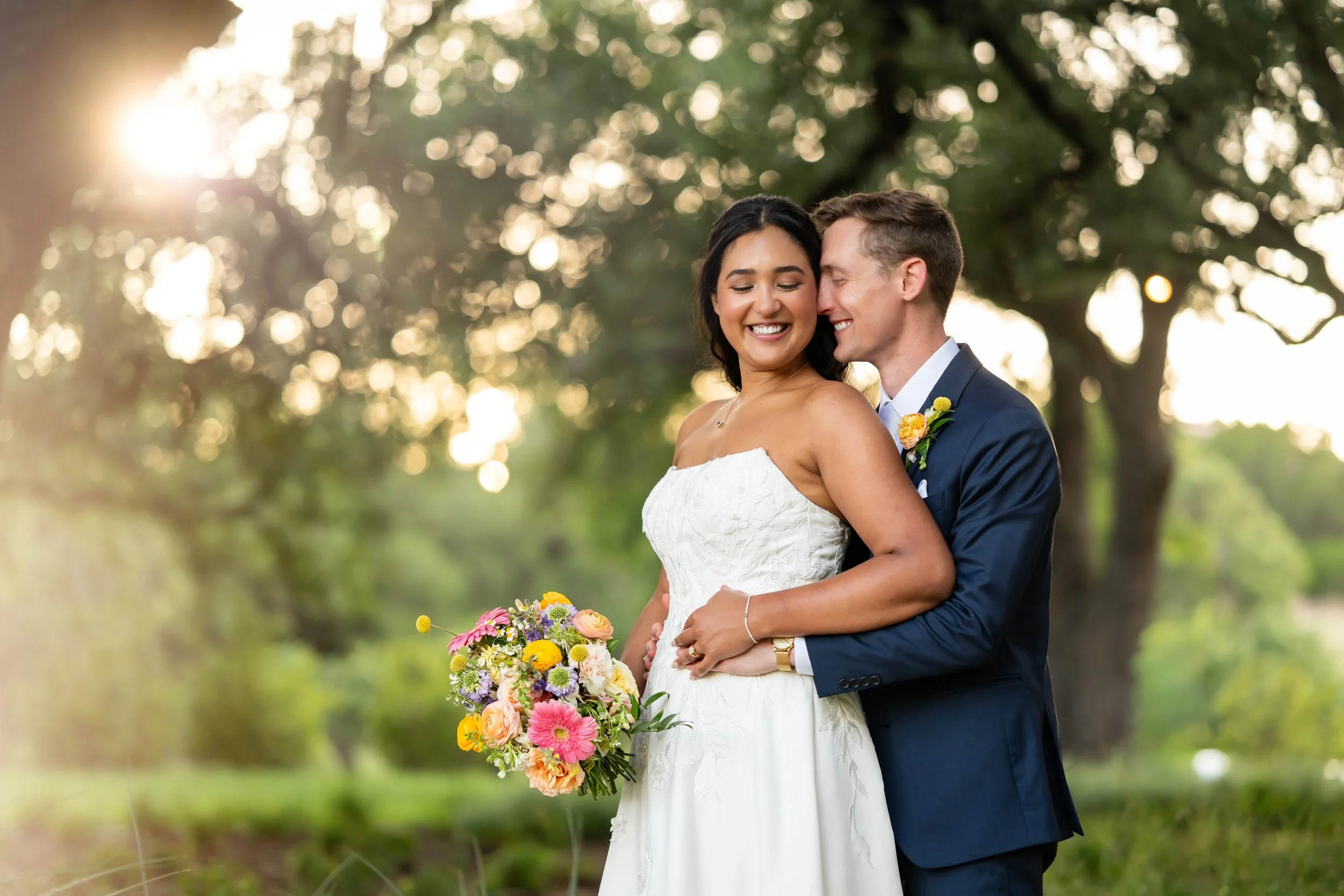 Bride and Groom under the trees with pastel floral bouquet
