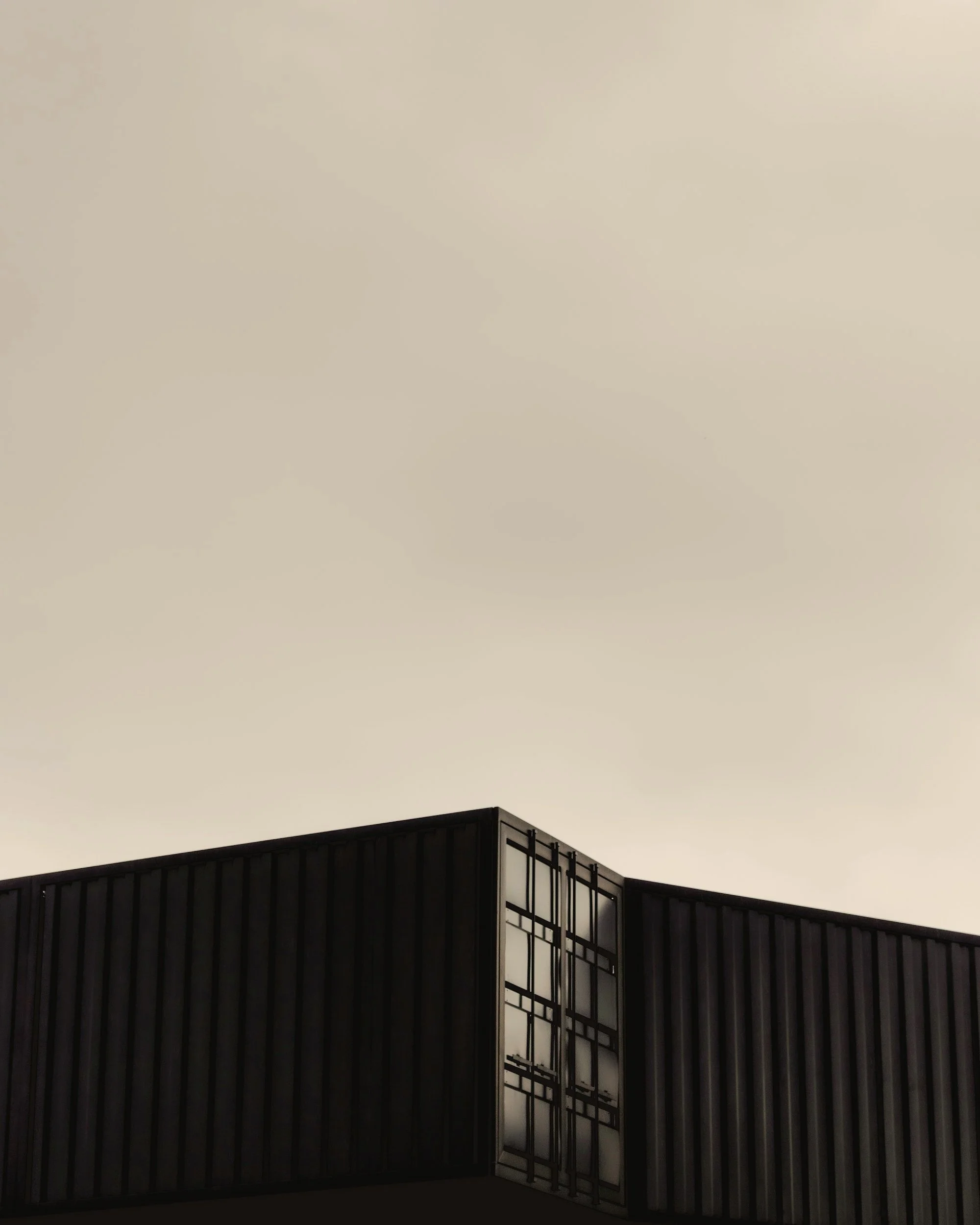 Modern building corner with glass and metal facade against cloudy sky.