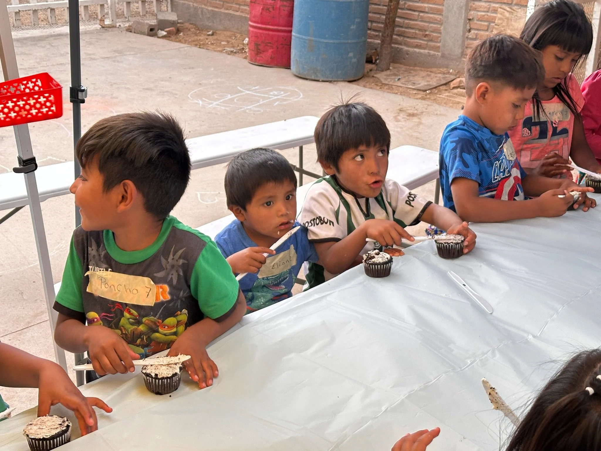 Children sitting at a table with cupcakes during a birthday celebration