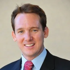 A man in a suit smiling at the camera.