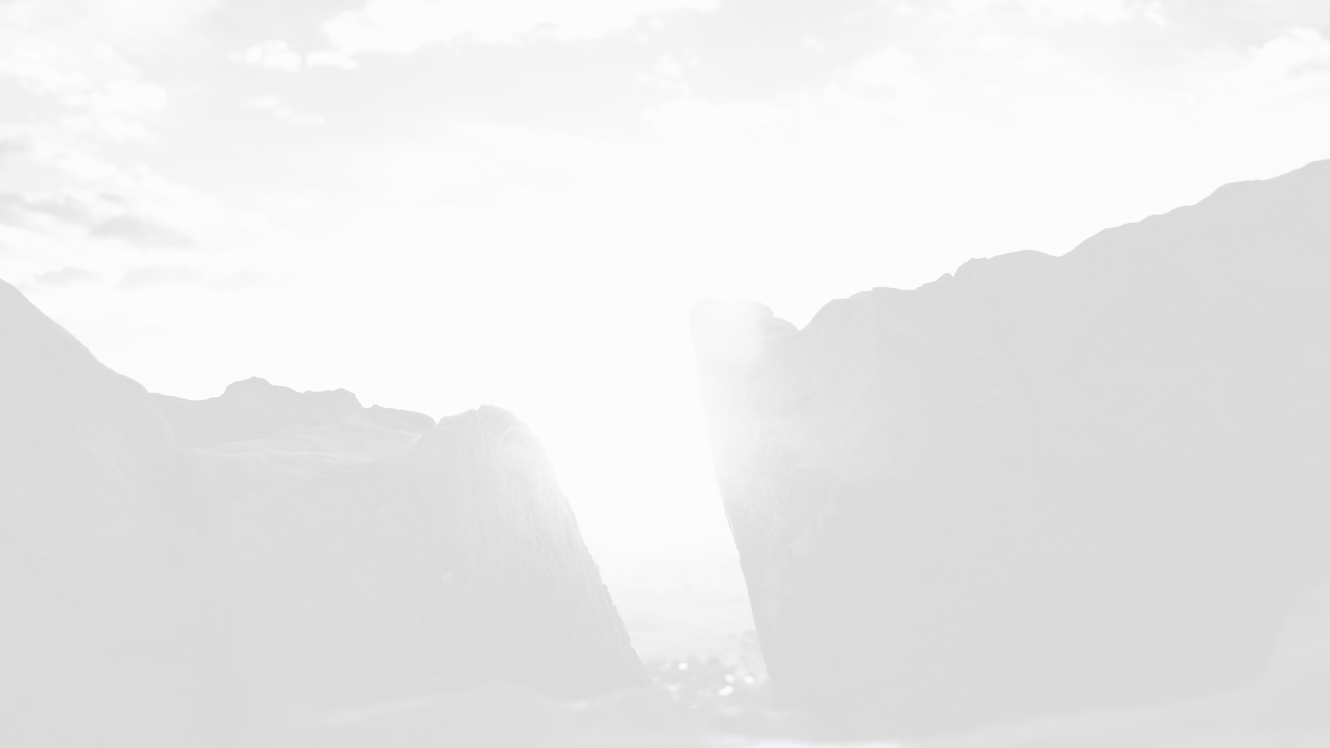 Scenic view of a deep canyon with steep cliffs on each side, and a narrow pathway or river at the bottom, under a partly cloudy sky.