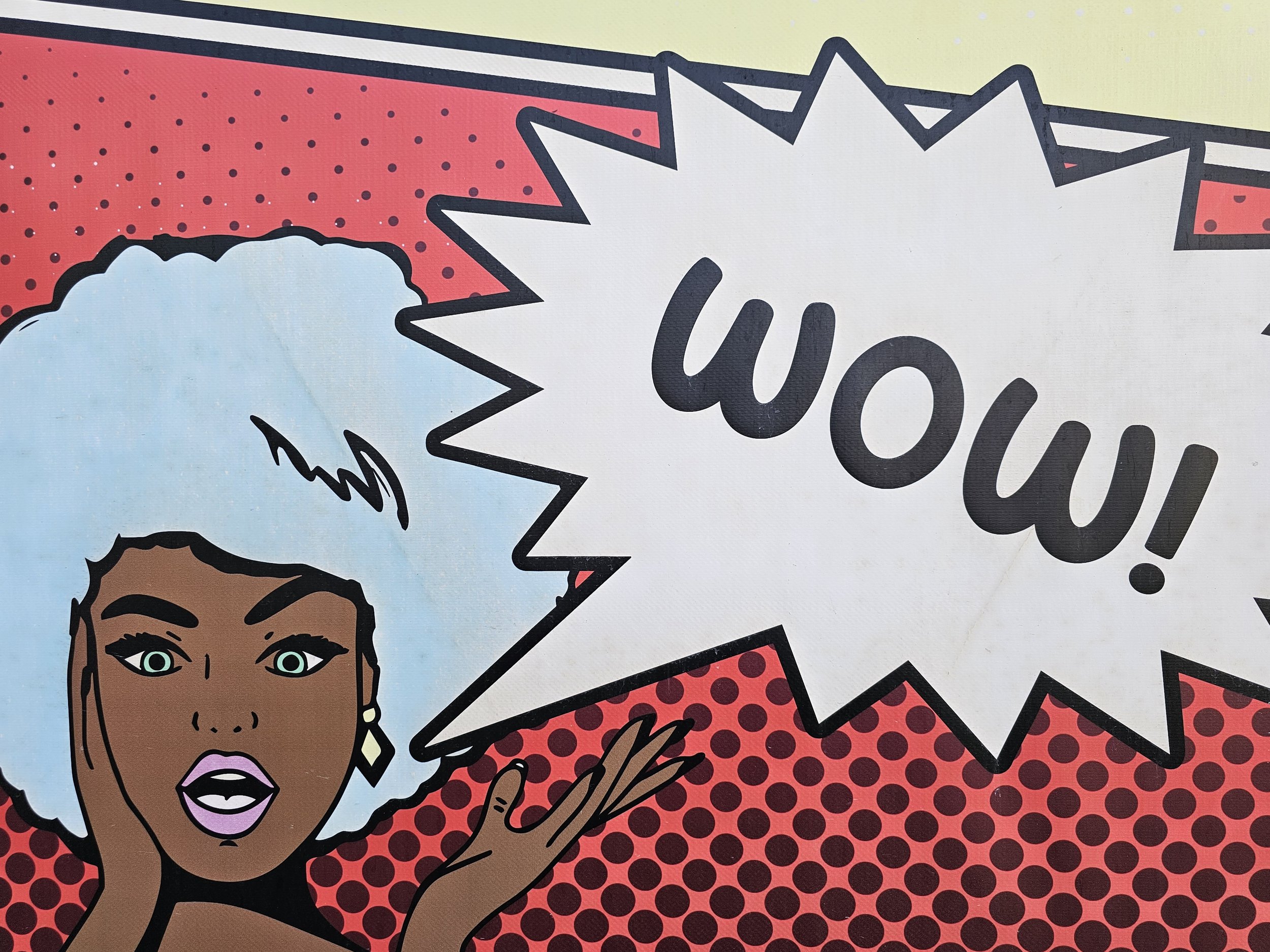 Pop art comic-style illustration of a woman with light blue hair, expressive eyes and makeup, speaking with a speech bubble that says "Wow!" against a red polka dot background.