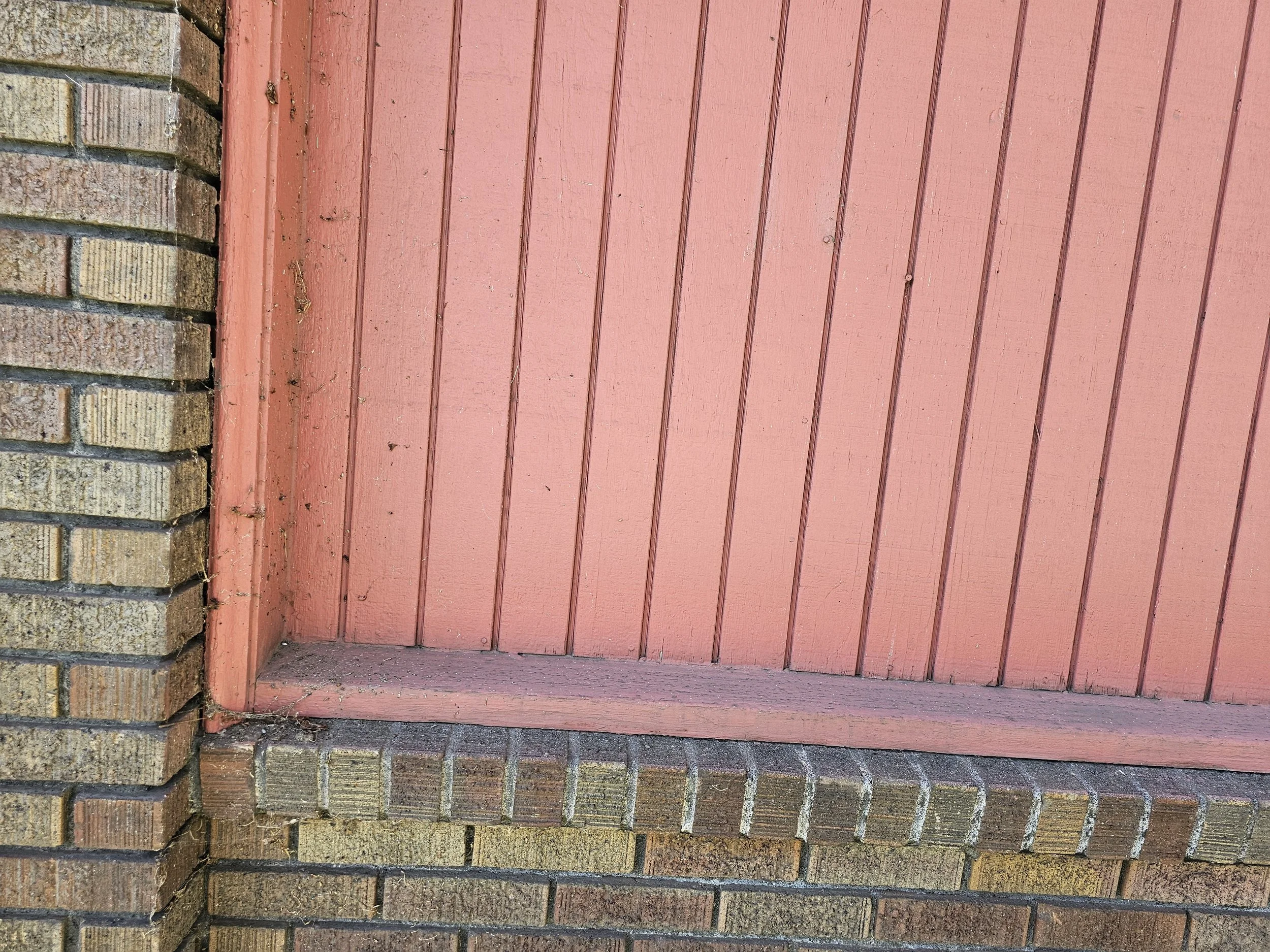 Close-up of a brick wall and a pink wooden boarded surface.
