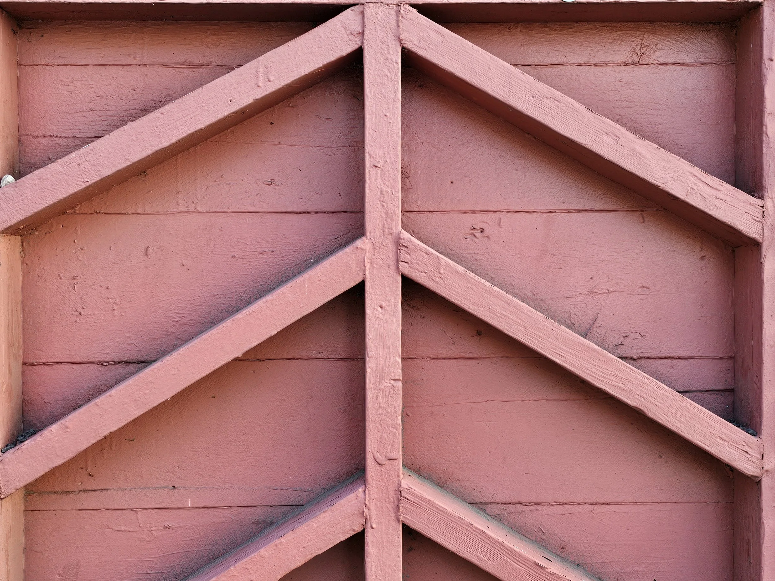 Close-up of a pink wooden lattice or decorative panel, showing horizontal and diagonal wooden slats.