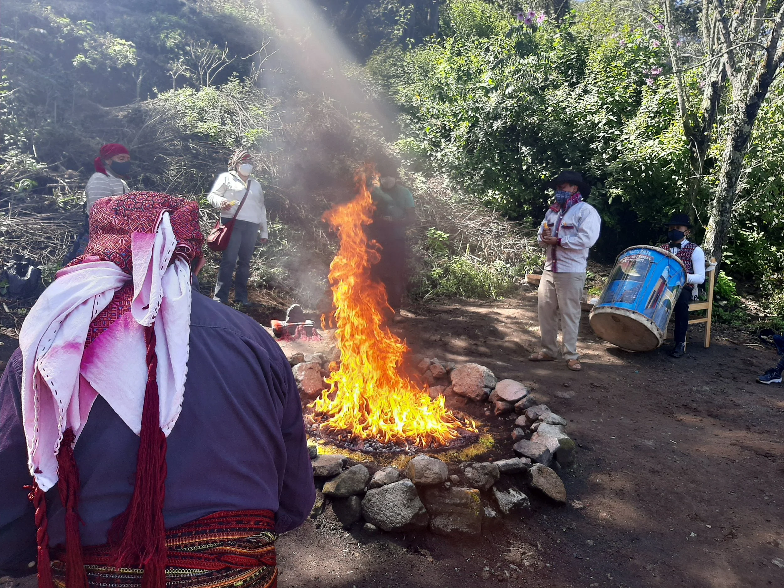 A circle of candles on fire on a dark surface, with flames rising from the center.