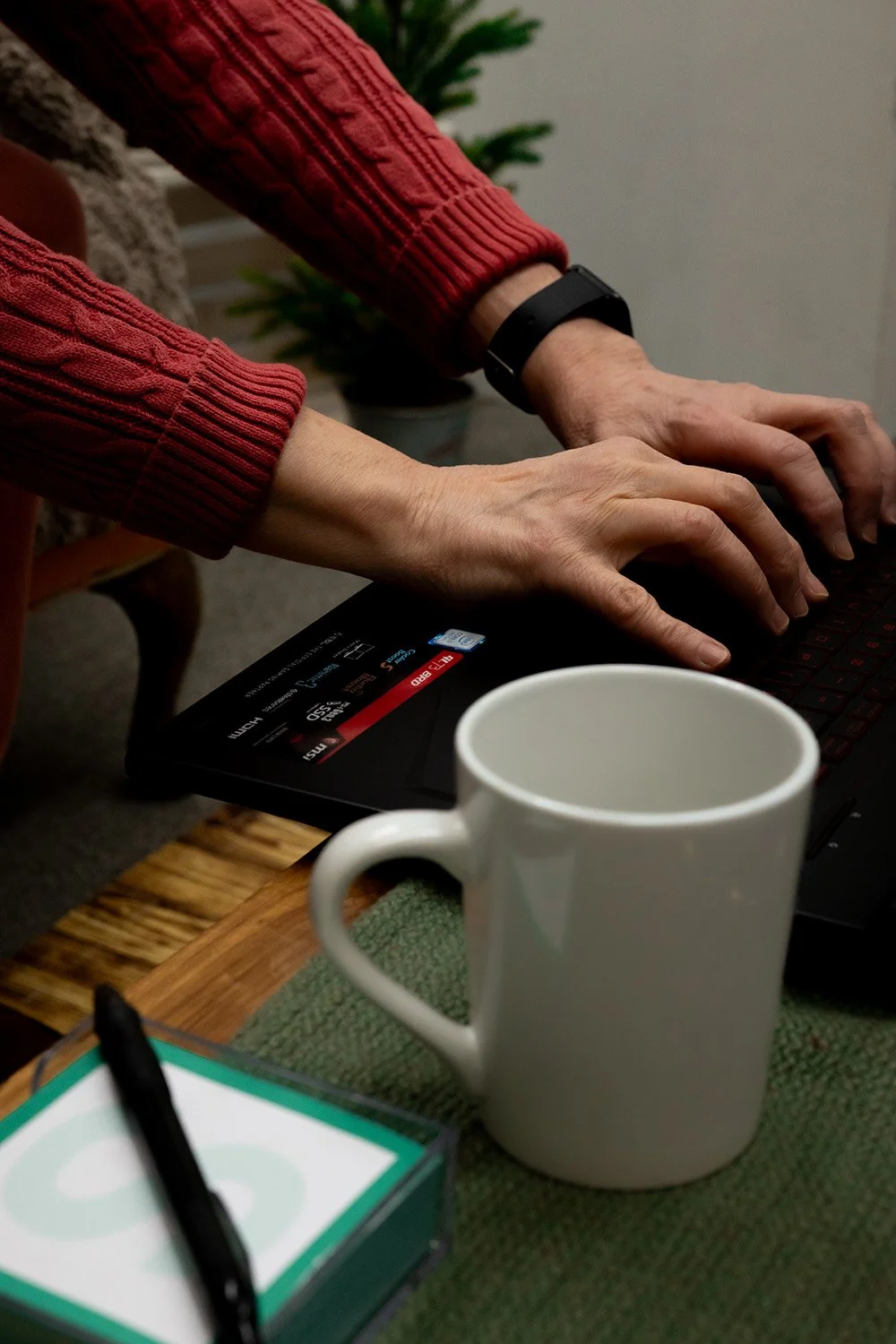 Rural Nurse Writer Dana Plank's hands typing on a computer with a mug in the foreground