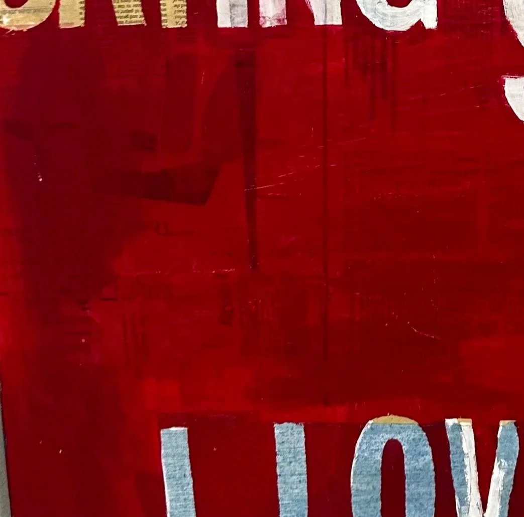Close up of a painting in red hues words with some letters, maybe spelling love, cut off on the bottom