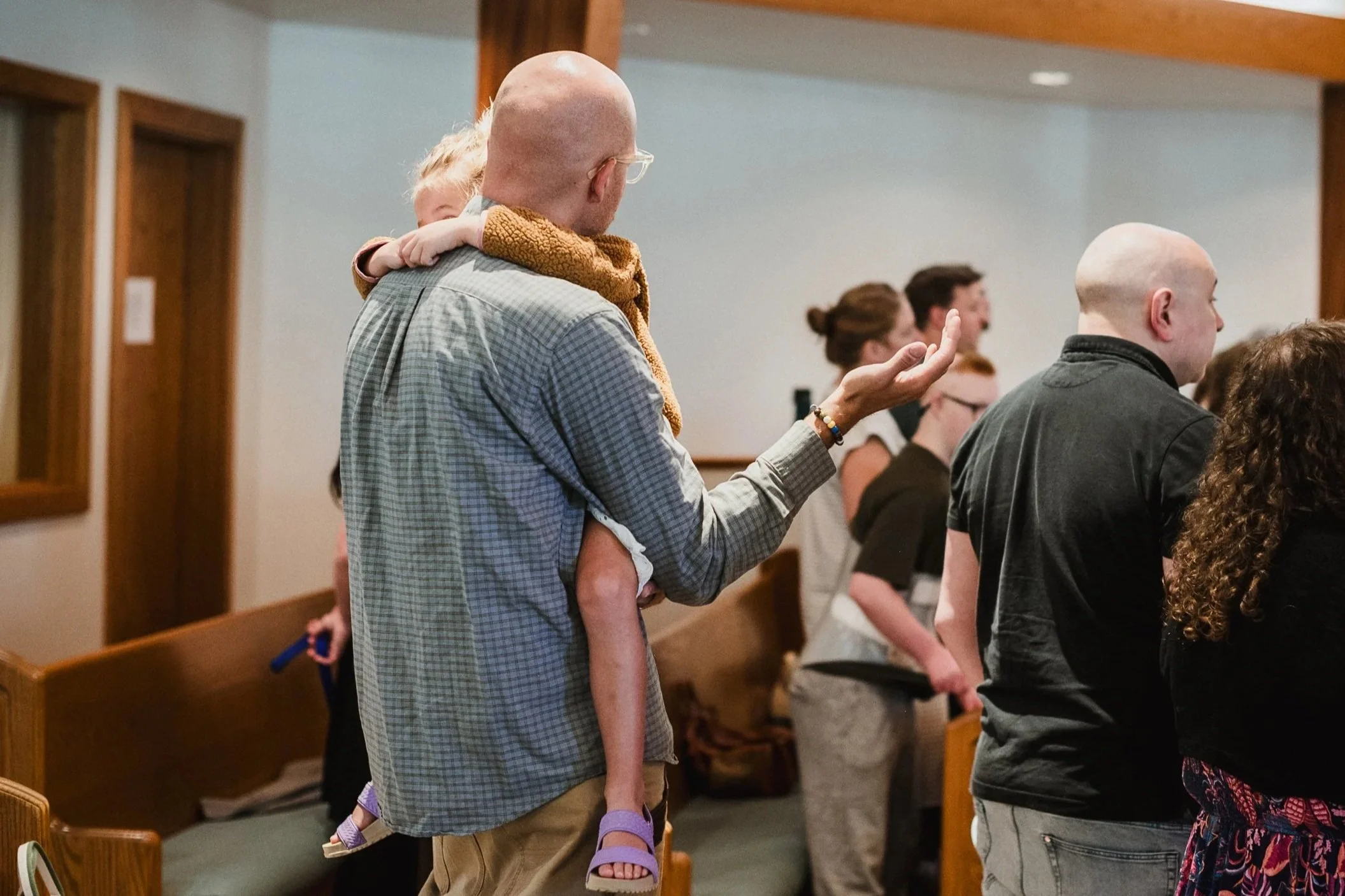Person's hands clasped over an open book on a wooden table