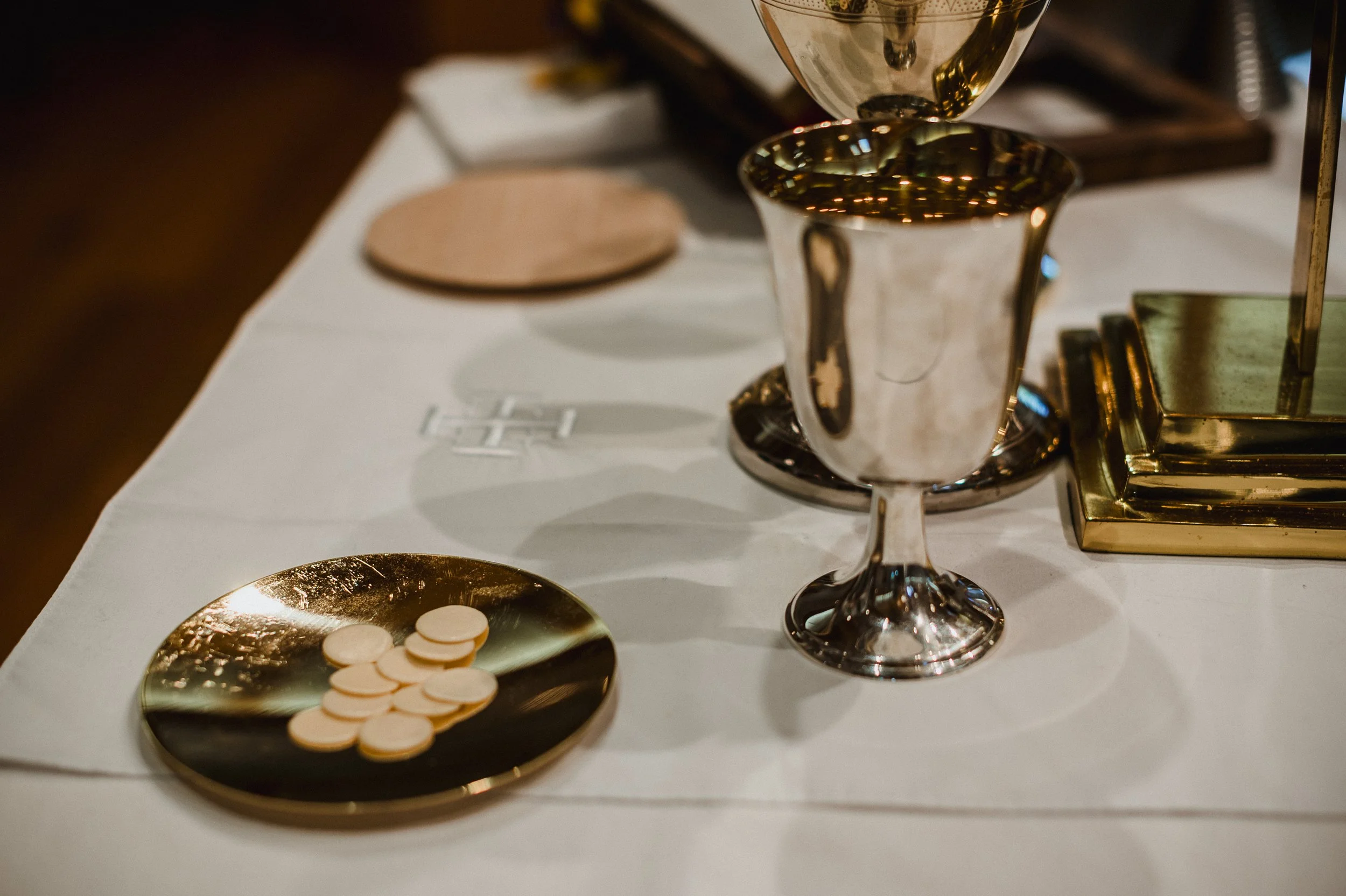 Gold chalice with red liquid and a ciborium with communion wafers on a white surface