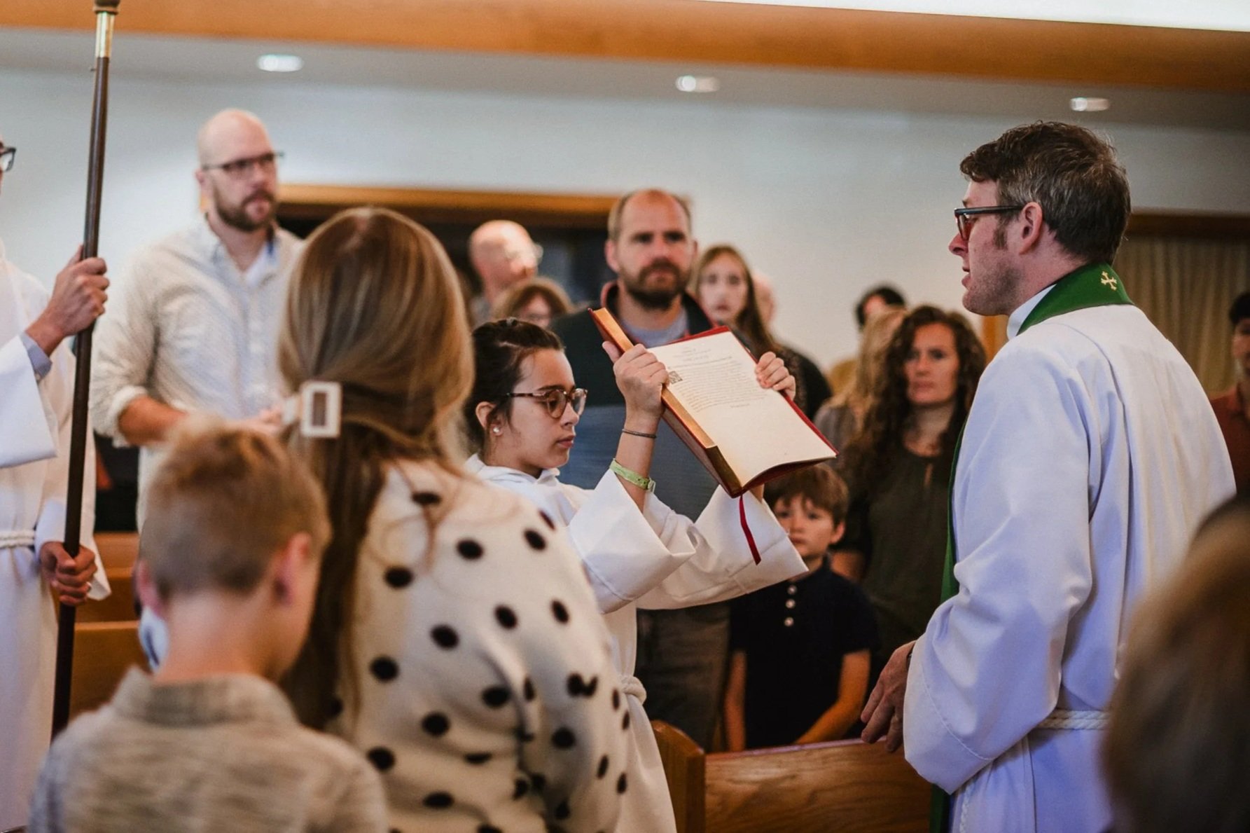 Open book with visible text, accompanied by a branch with green leaves.