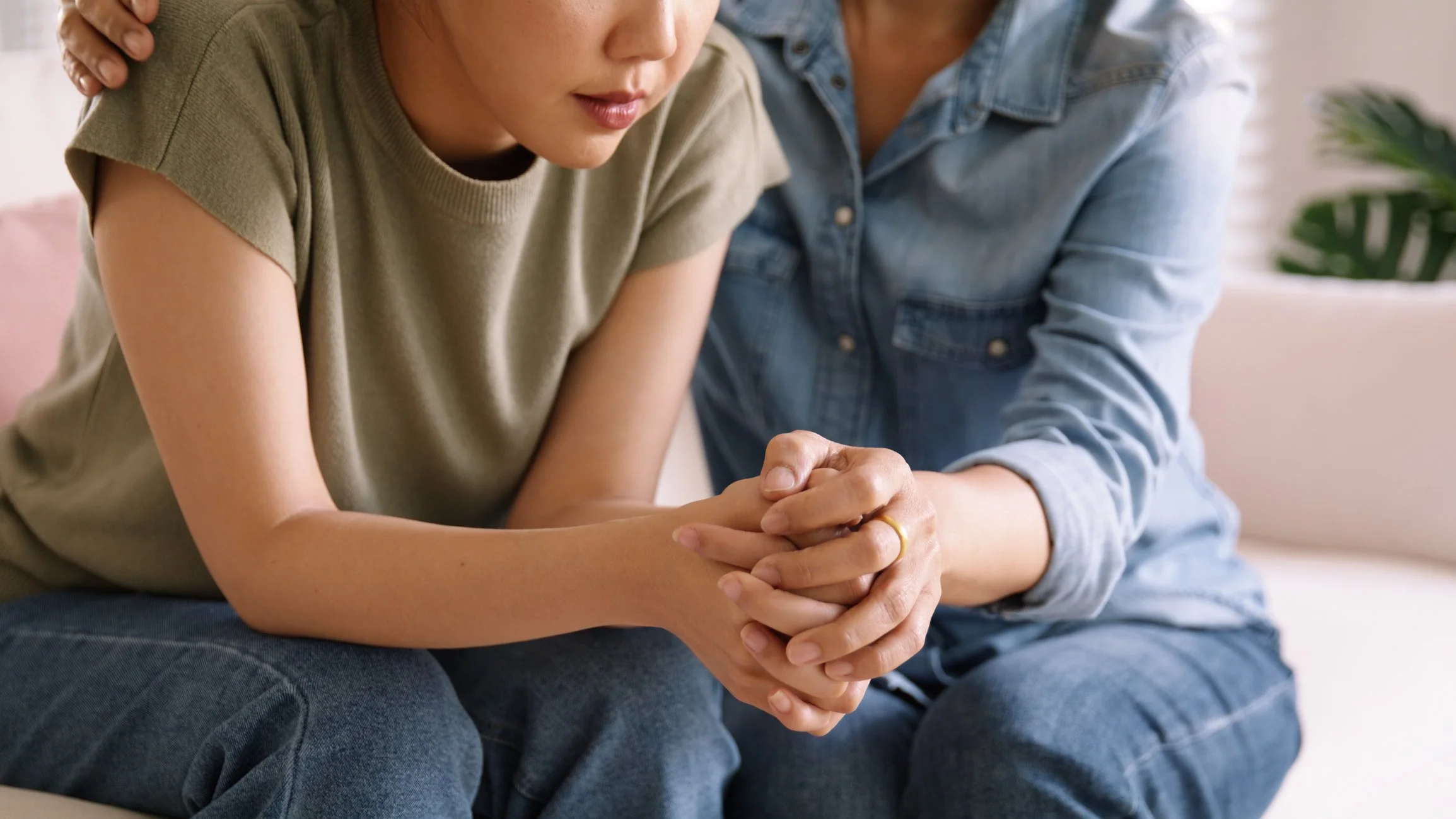 A woman providing comfort to a teen or child, holding her hands in a supportive gesture. Therapy can help.
