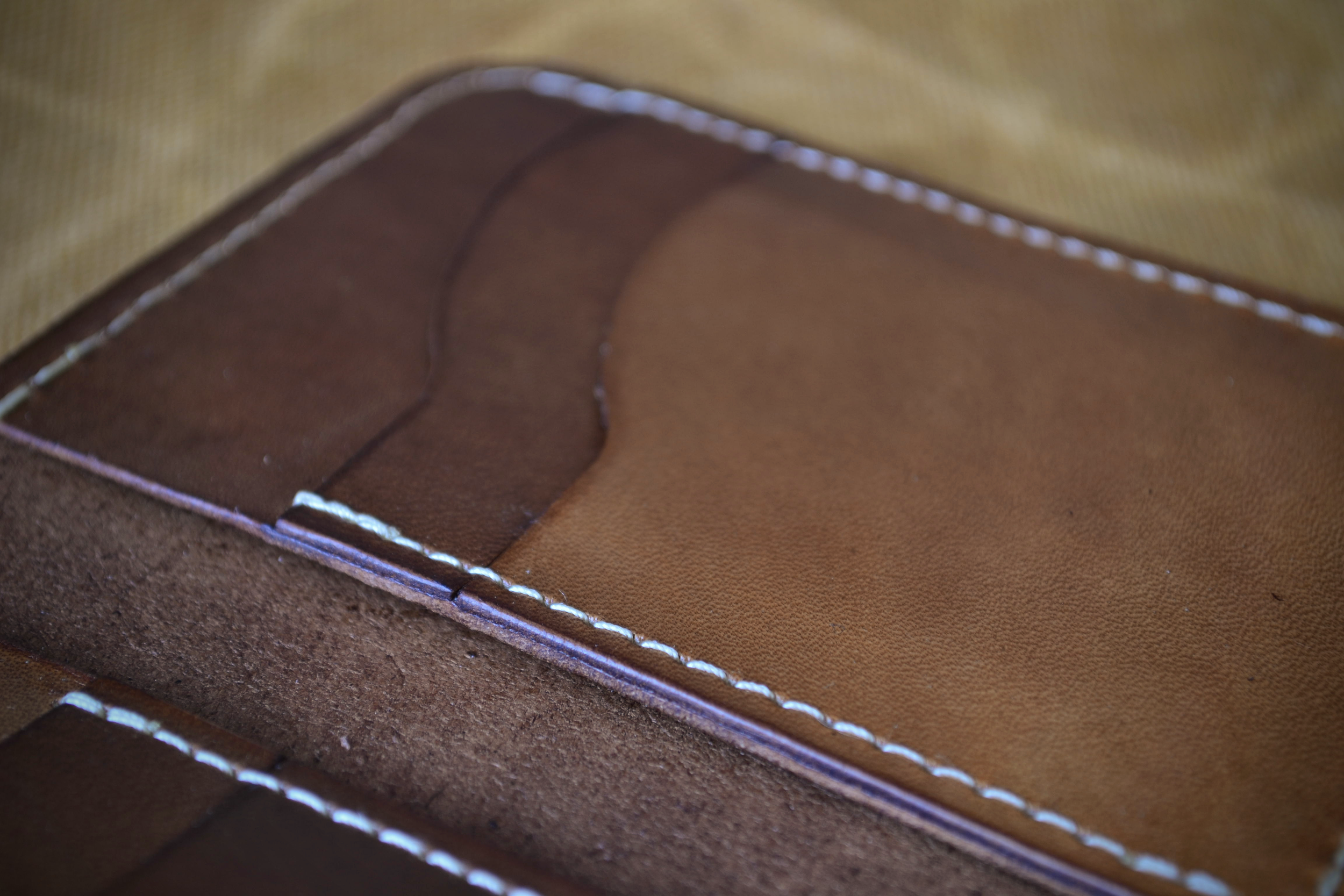 Close-up of a brown leather wallet showing an empty card slot with white stitching.