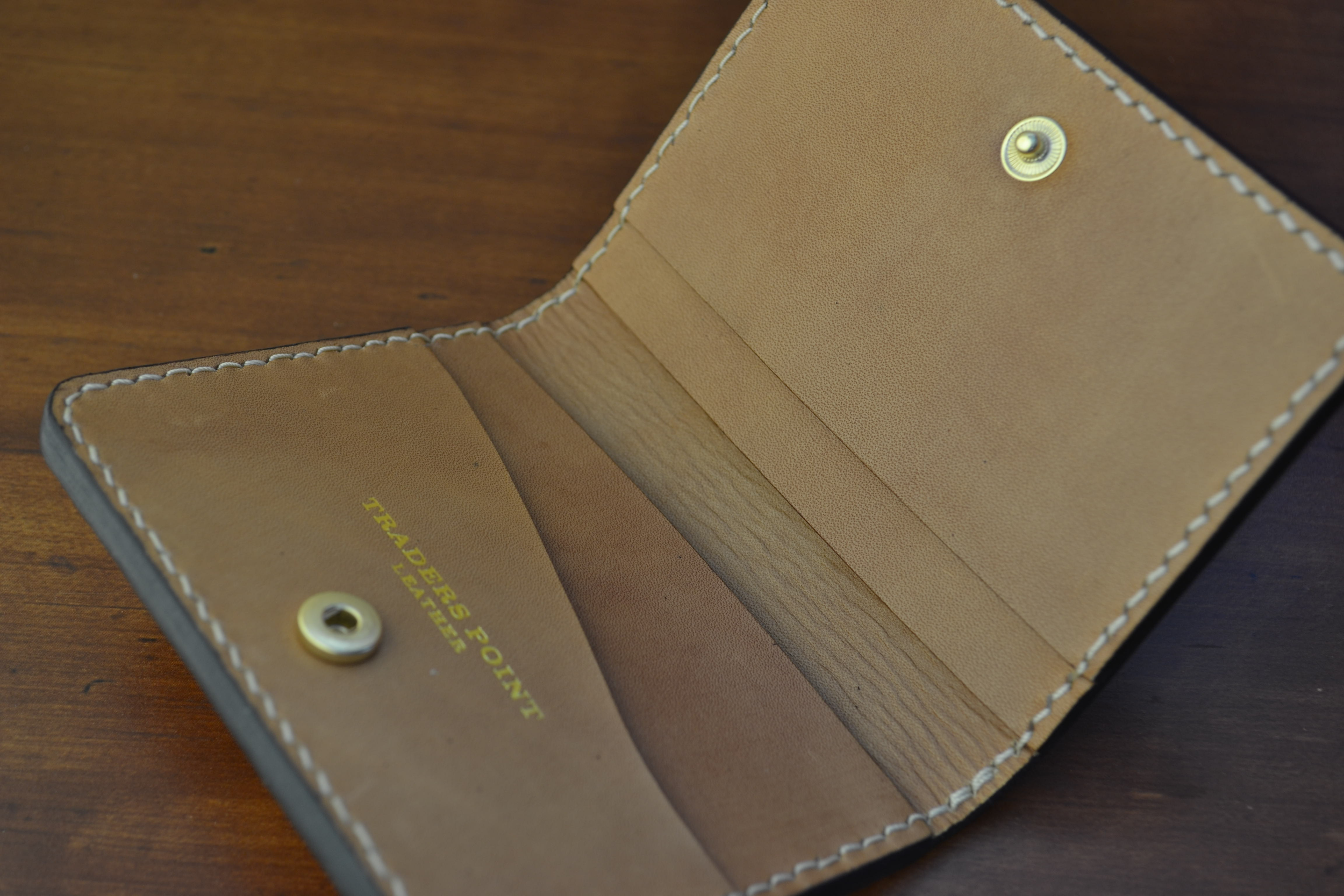Open leather wallet showing inside compartments and the inscription 'TRADERS POINT LEATHER' in gold lettering.