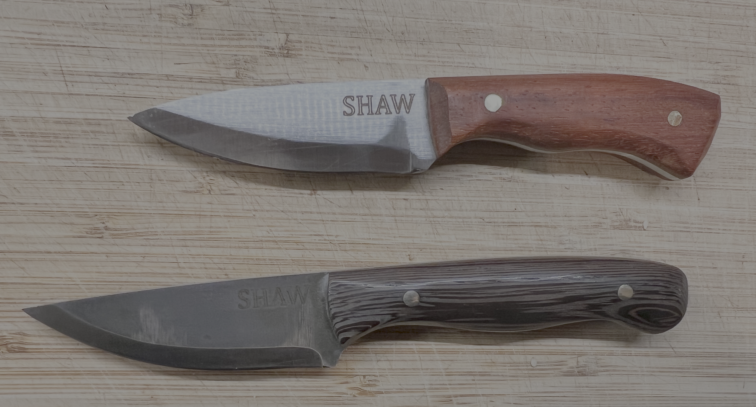 Two kitchen knives with wooden handles resting on a wooden cutting board.