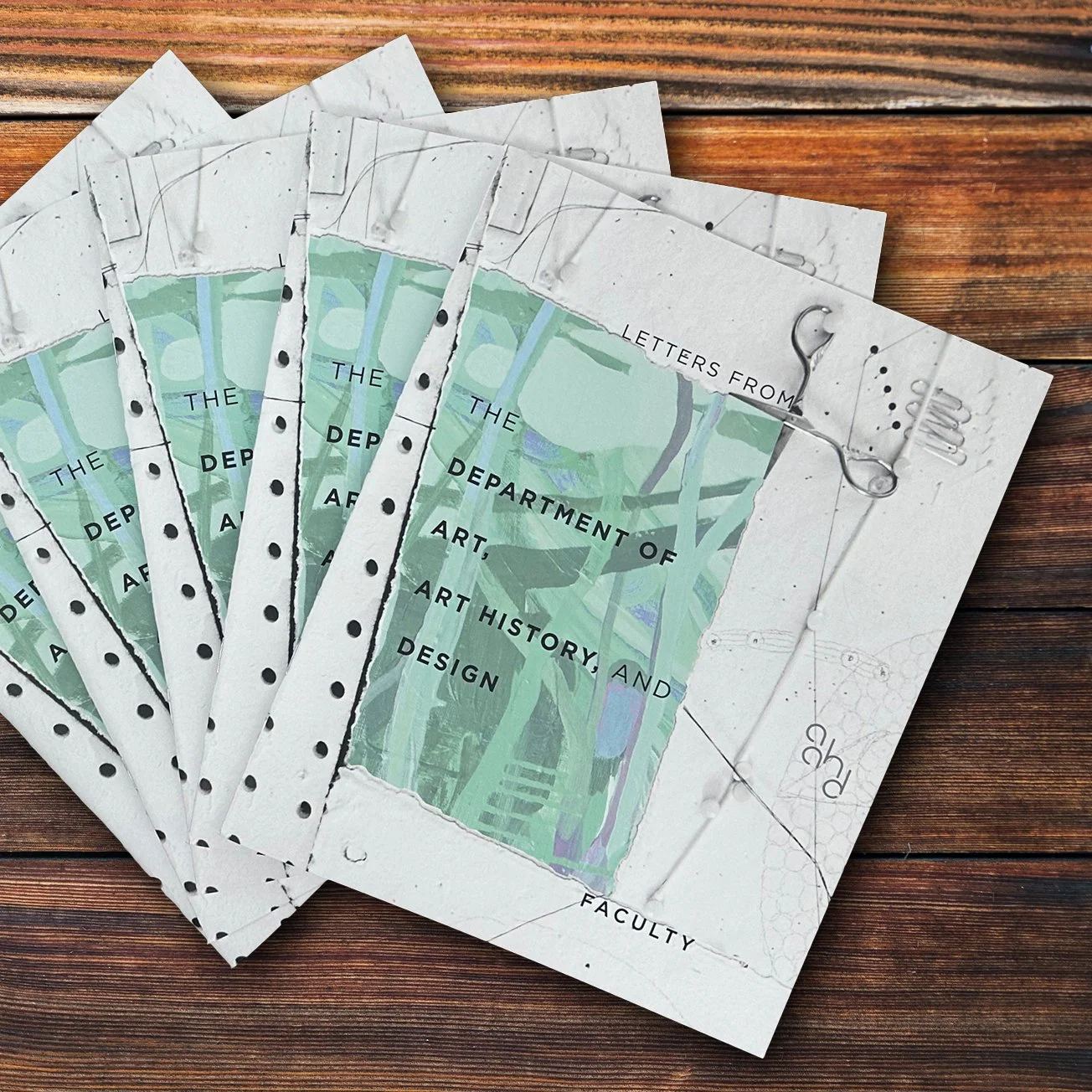 Brochures titled 'Letters from the Department of Art, Art History and Design Faculty' on a wooden surface.