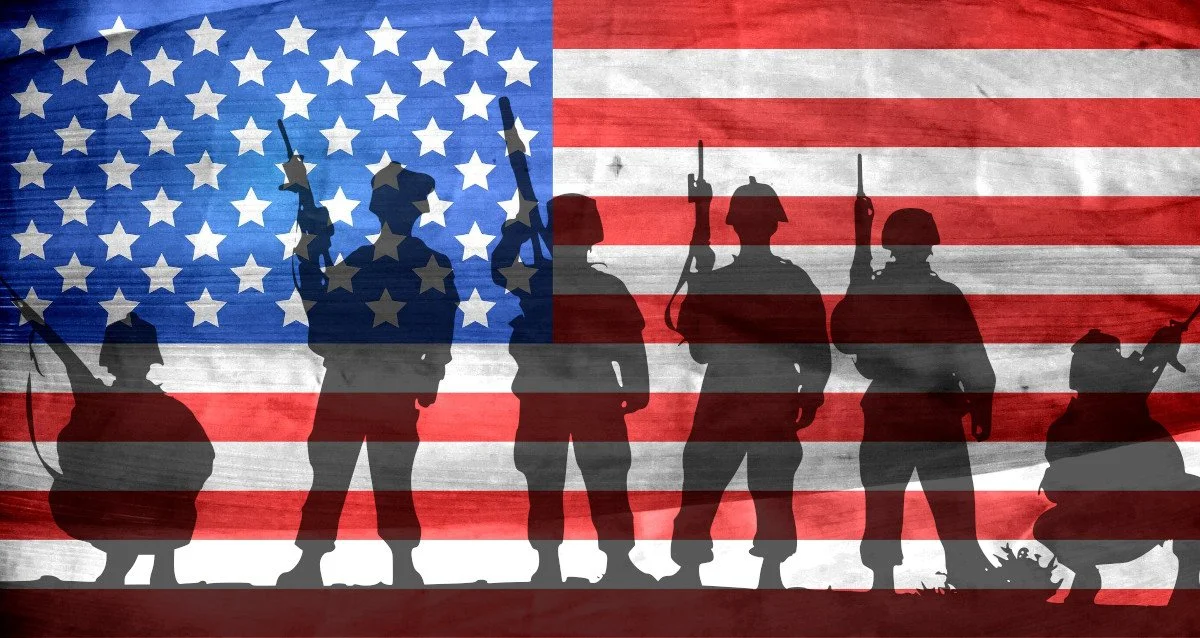 Silhouettes of soldiers holding guns against a background of the American flag.