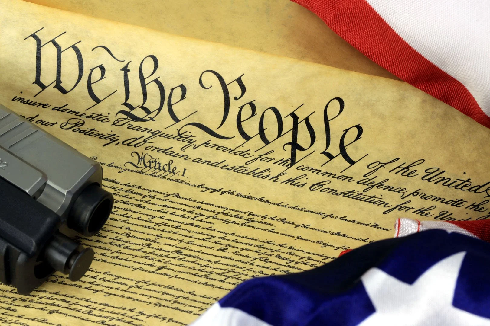 Close-up of the United States Constitution with a firearm and American flags. Constitution. Gunsmith