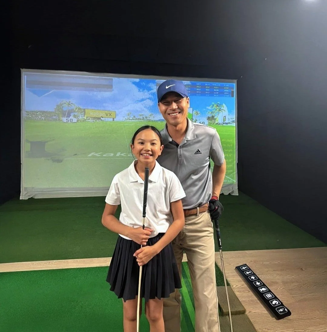 female student holding golf club next to golf instructor