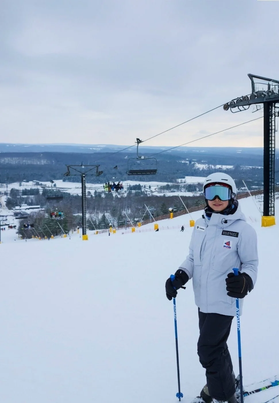 ski student standing on ski slope holding poles