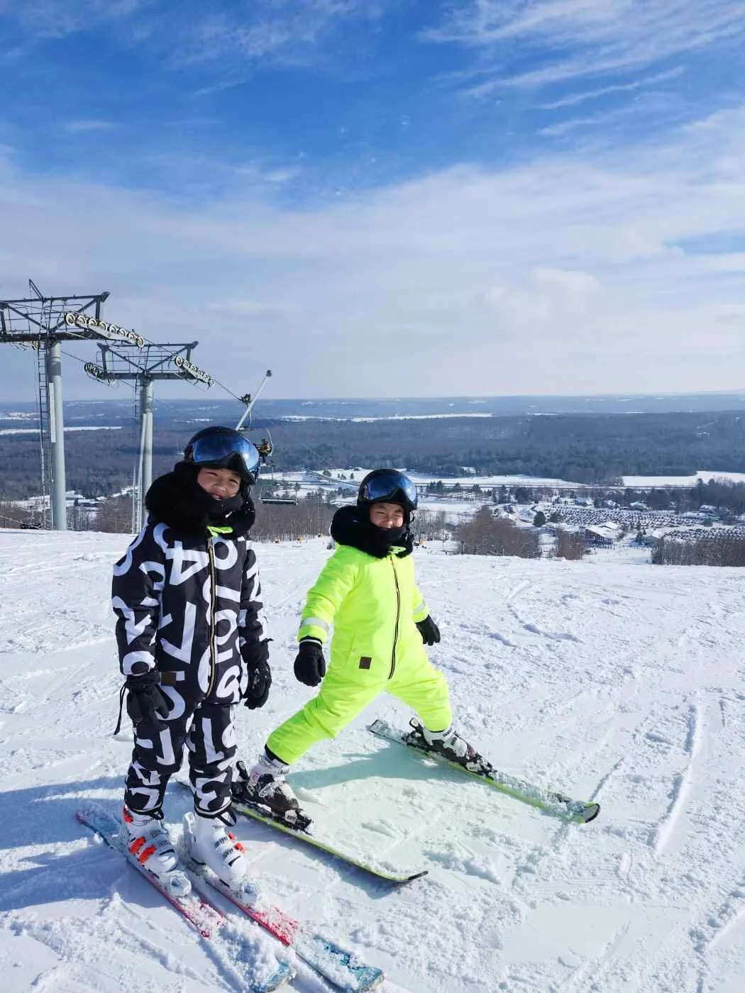 two students smiling on top of a ski slope