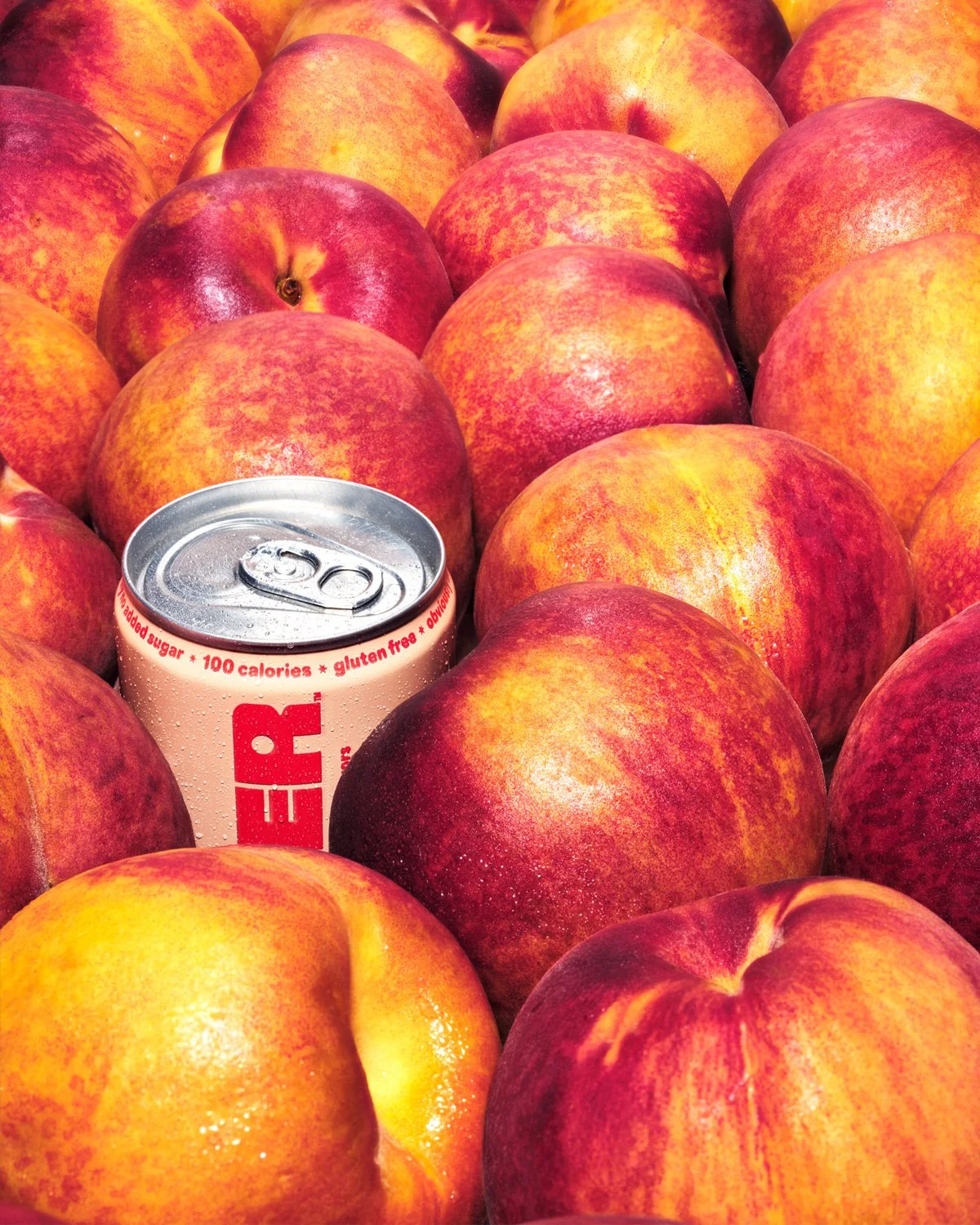 Composition of juicy peaches with a peach flavored soda; photo campaign to announce peach flavored vodka soda from Sprinter