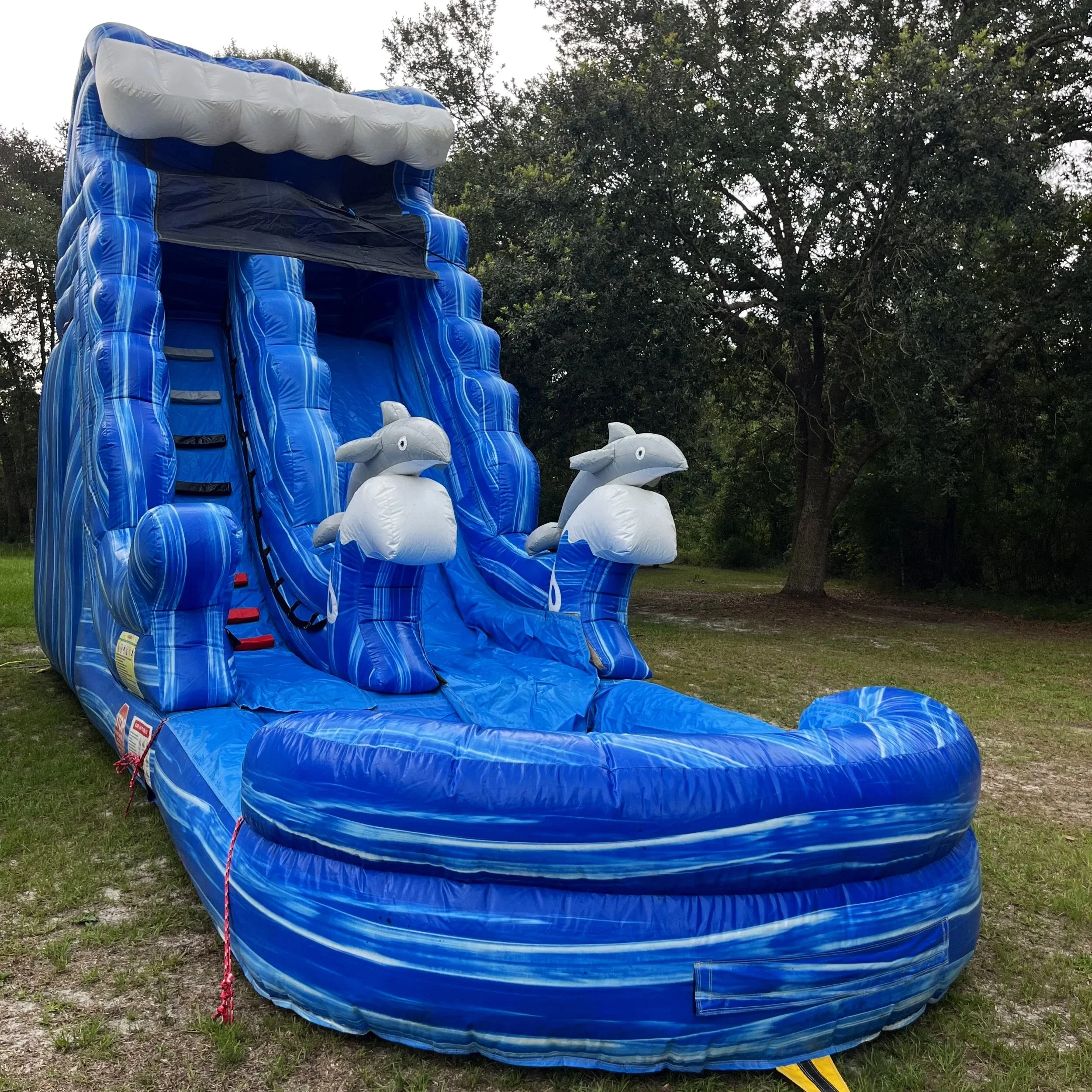 Big Flipper water slide rental photographed at sunset, highlighting its bright blue wave theme.