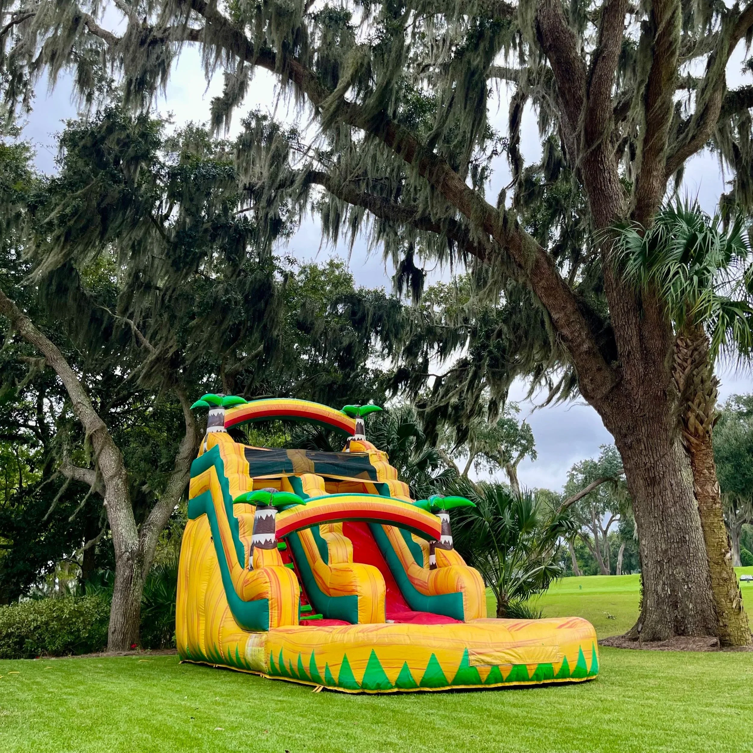 Front view of Sunshine Falls waterslide featuring bright yellow and green tropical colors with splash pool.