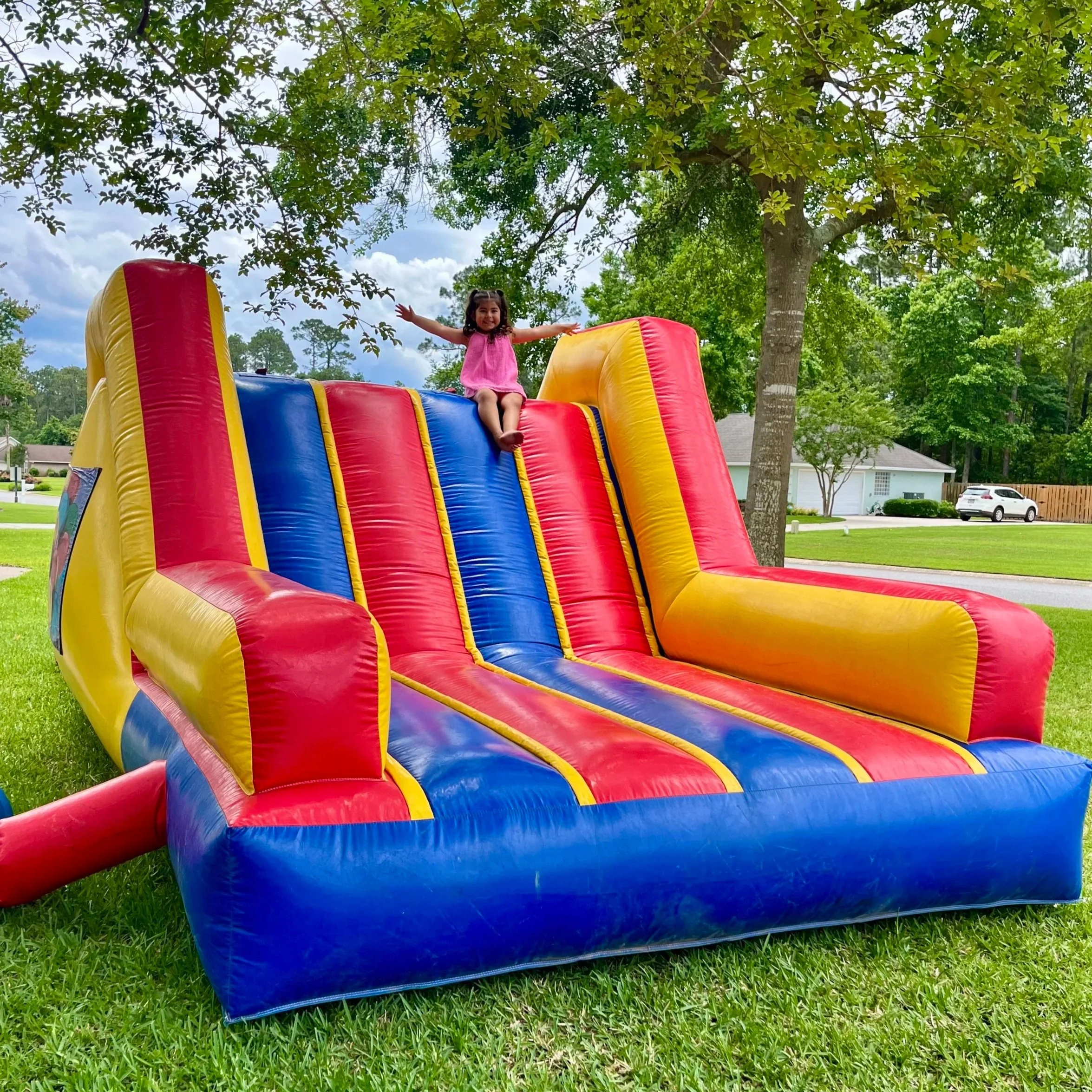Kids racing through the Pops Pavilion mini obstacle course with dual slides and rope obstacles at a backyard party in Brunswick, Georgia.