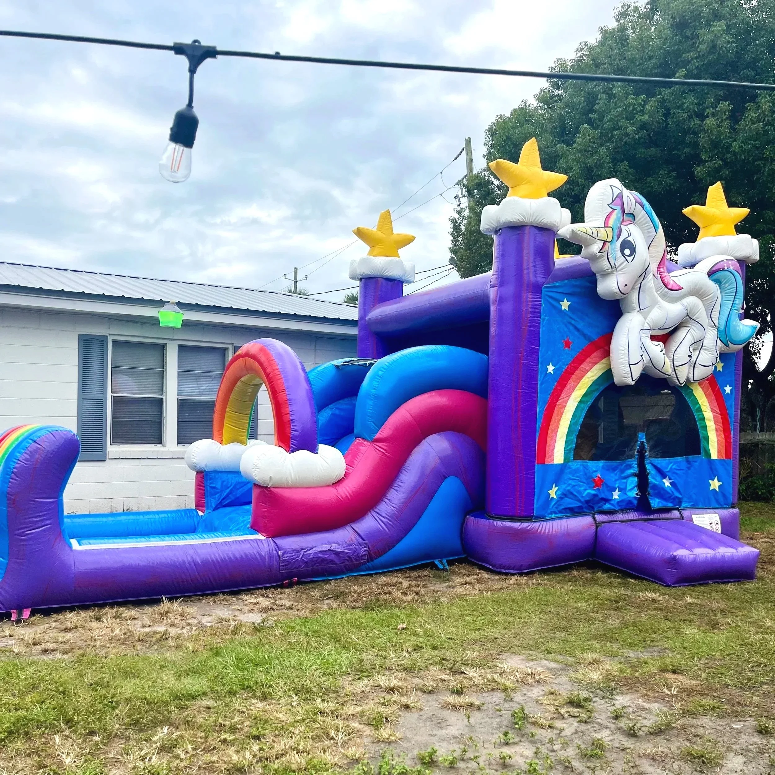 Colorful Unicorn Playland inflatable featuring rainbow details and attached slide, perfect for younger kids.
