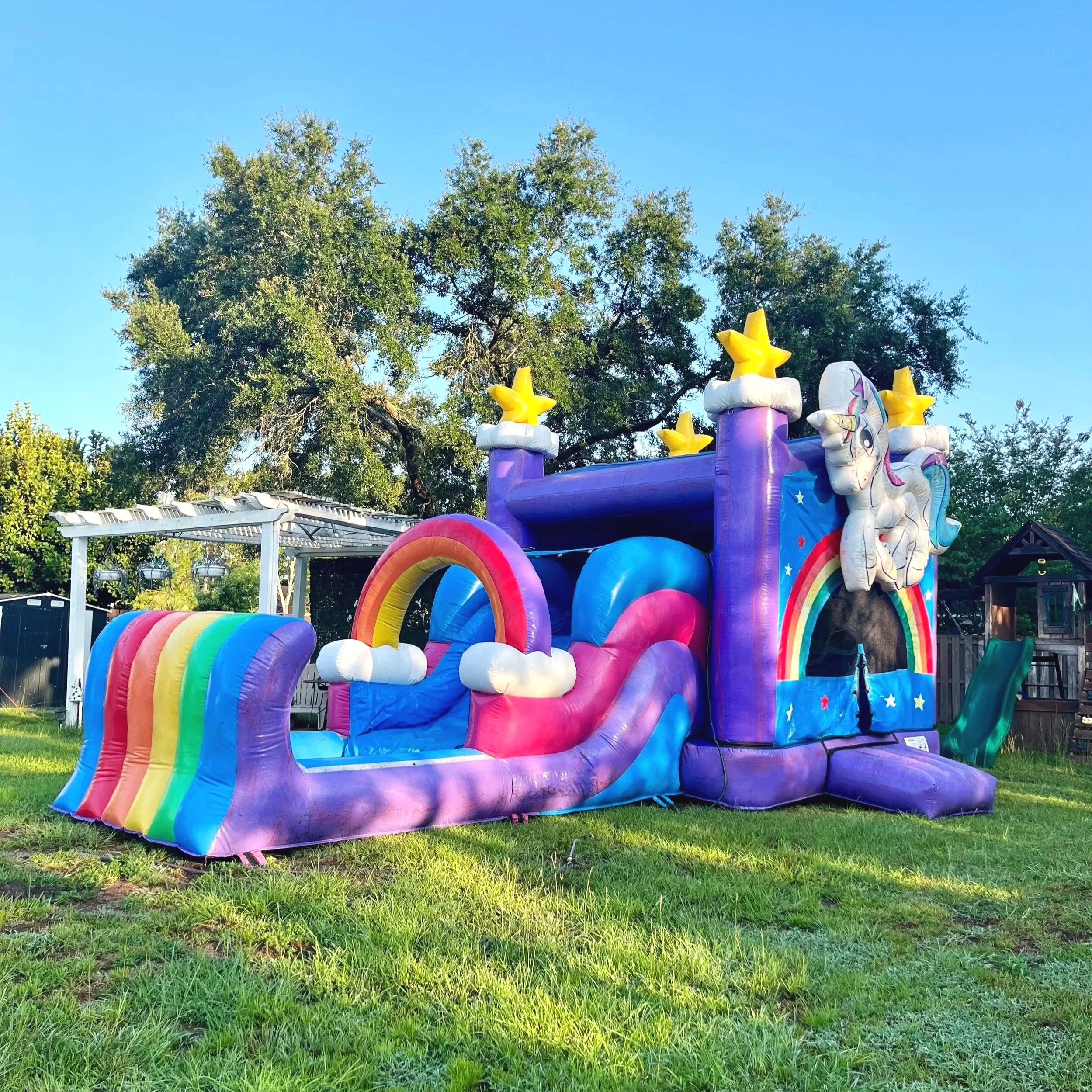 Side view of Unicorn Playland inflatable showing bounce area and slide in a residential backyard setup.