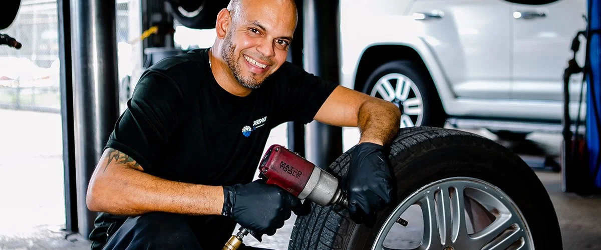 Auto Repair Pros technician smiles while he inspects a tire