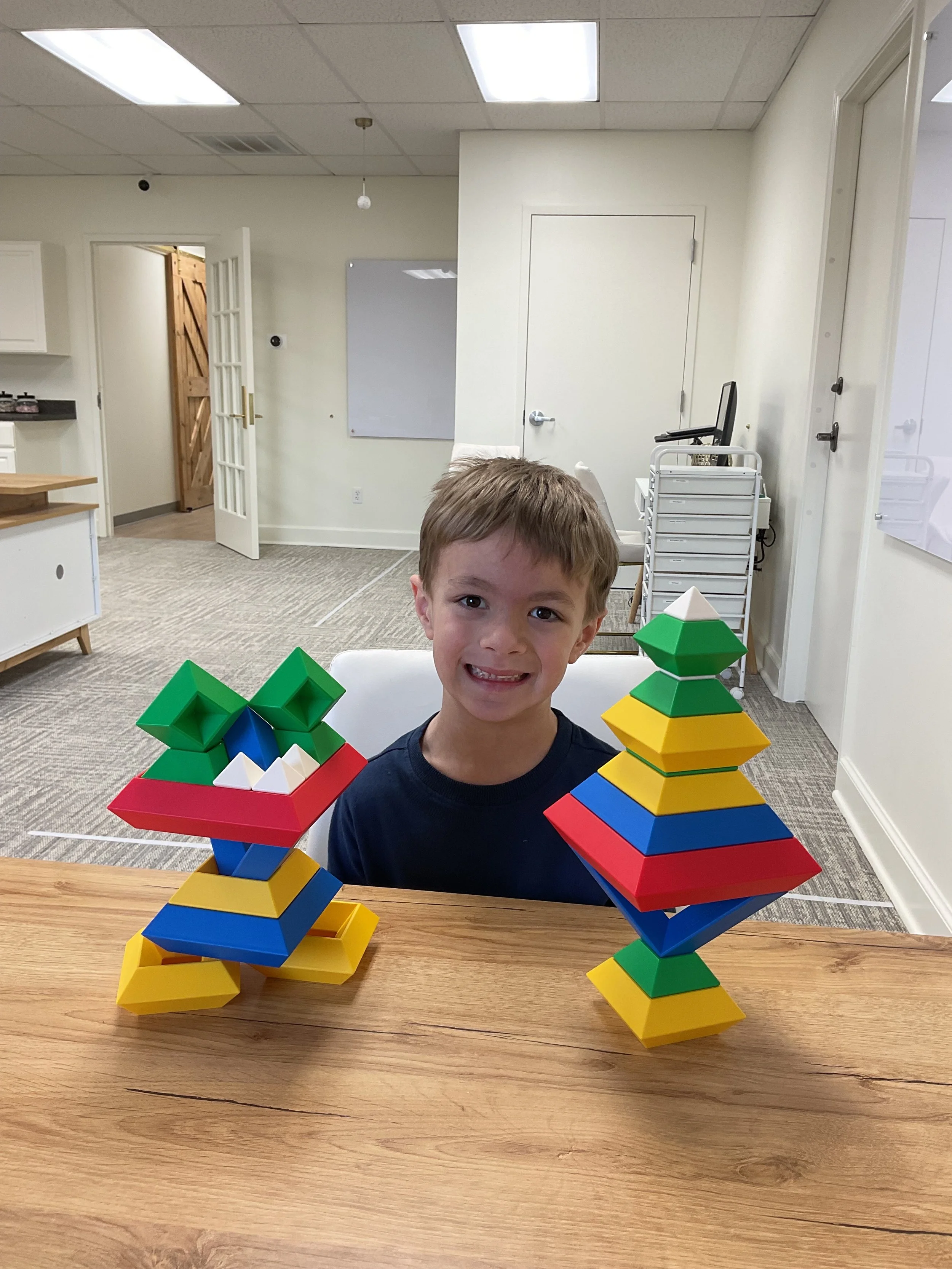 Young boy smiles with blocks he built.