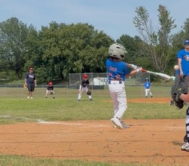Young boy playing baseball swings bat