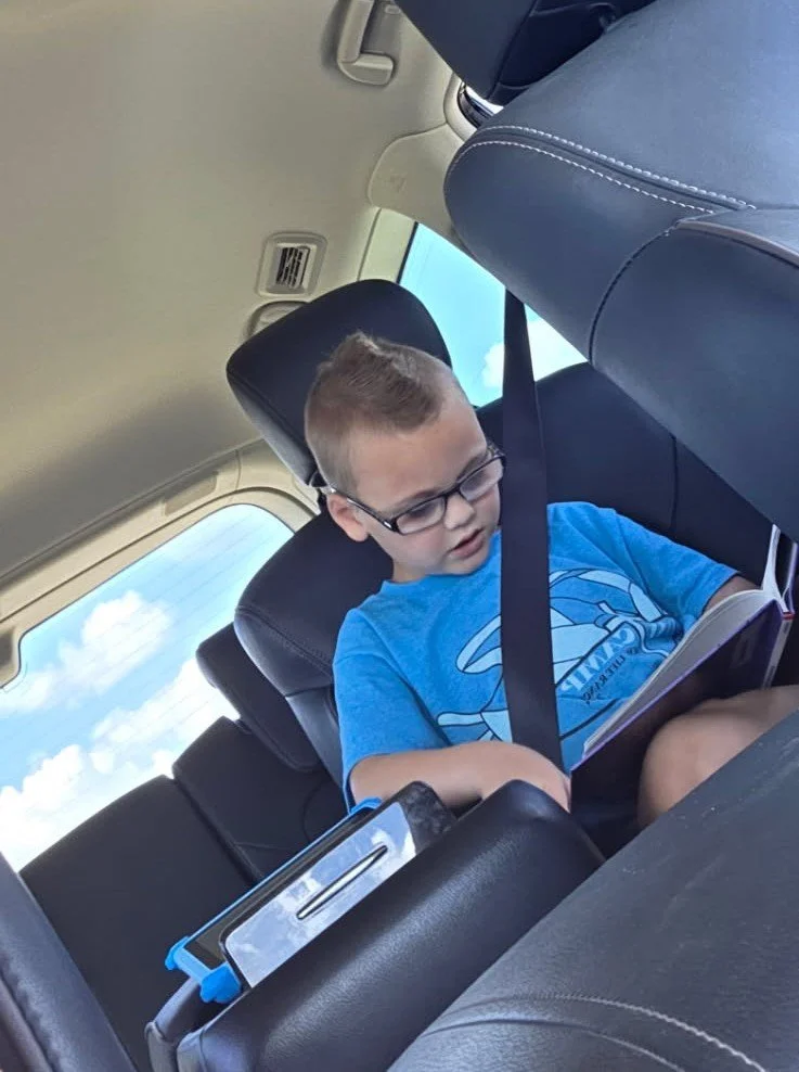 Young boy reads book in car
