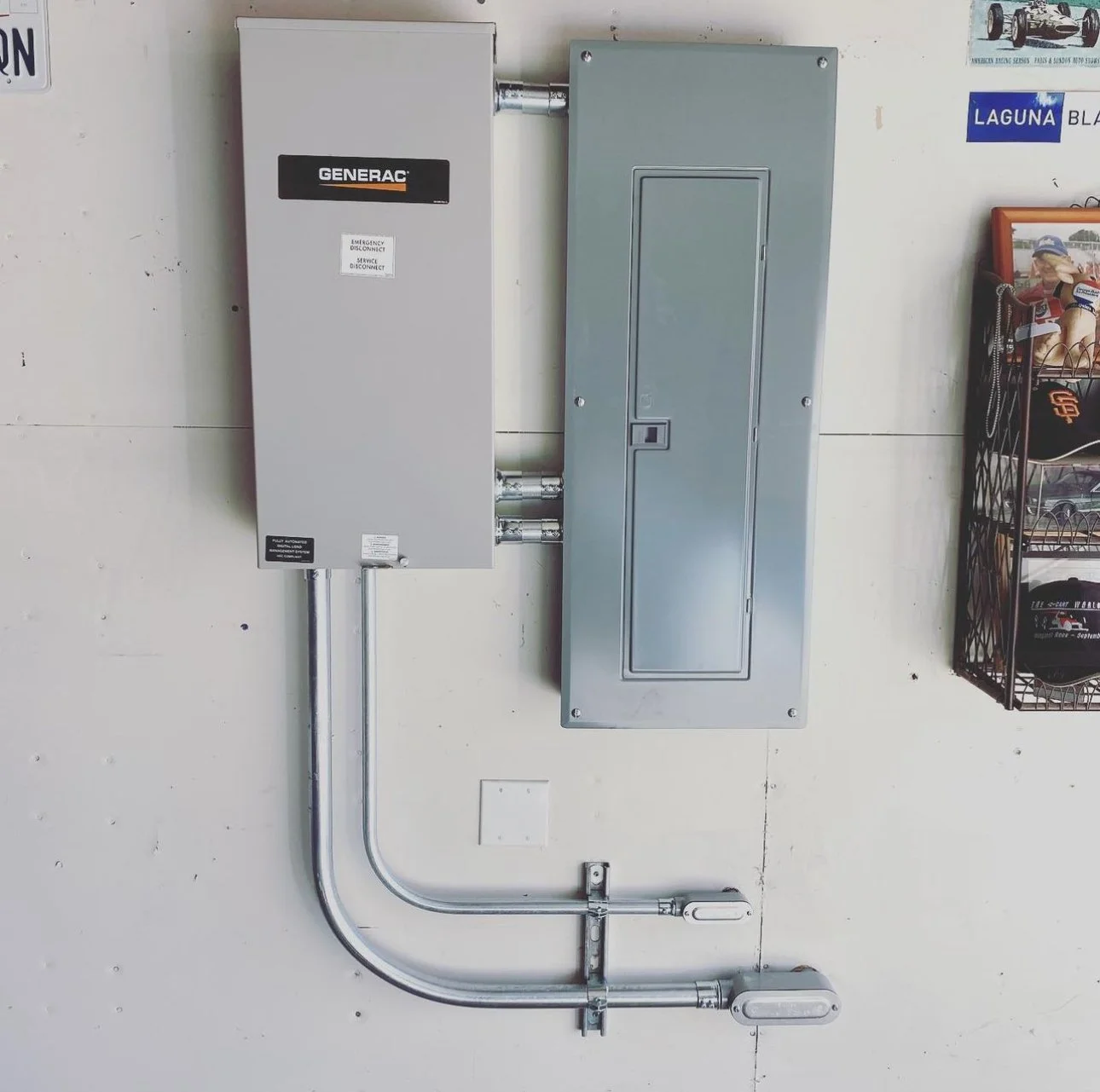 Electrical panel with Generac transfer switch and conduit on a wall.