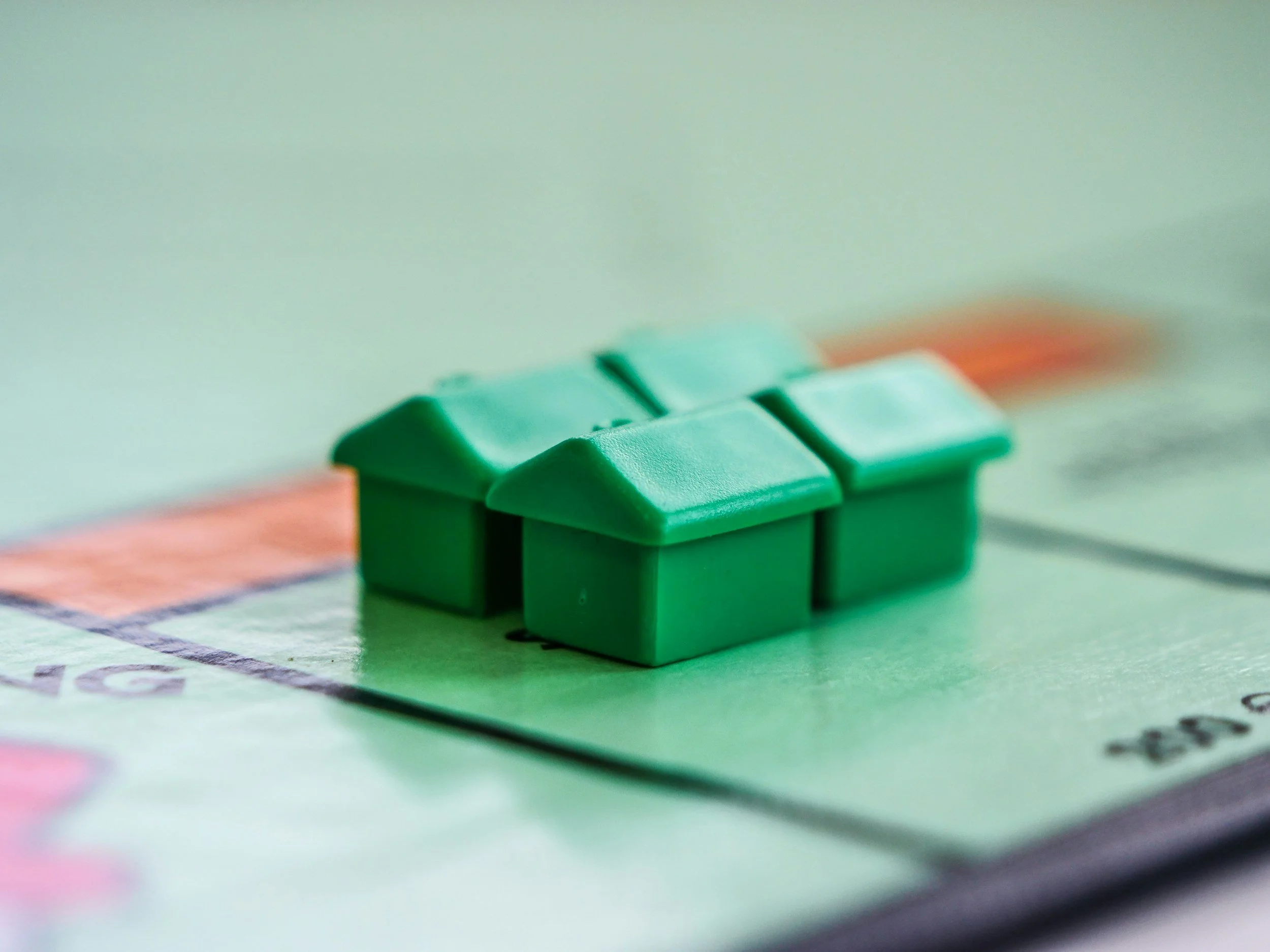 Close-up of green houses on a Monopoly game board.