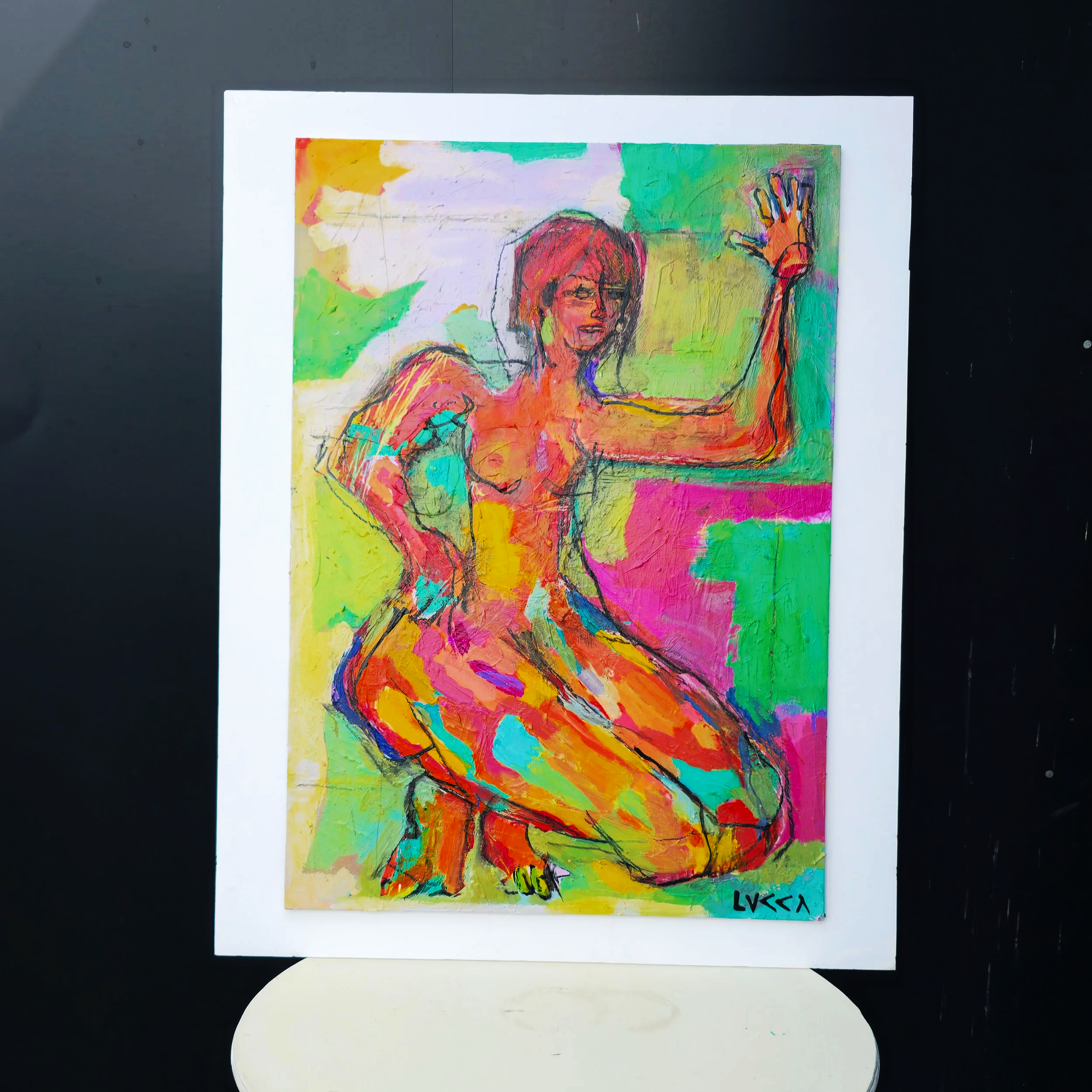 Colorful abstract painting of a woman with short hair, raising her hand, signed 'LUCCA' in the bottom right corner.