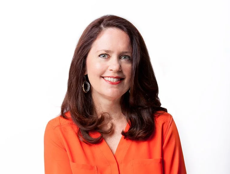 Smiling woman with shoulder-length brown hair wearing a green blouse