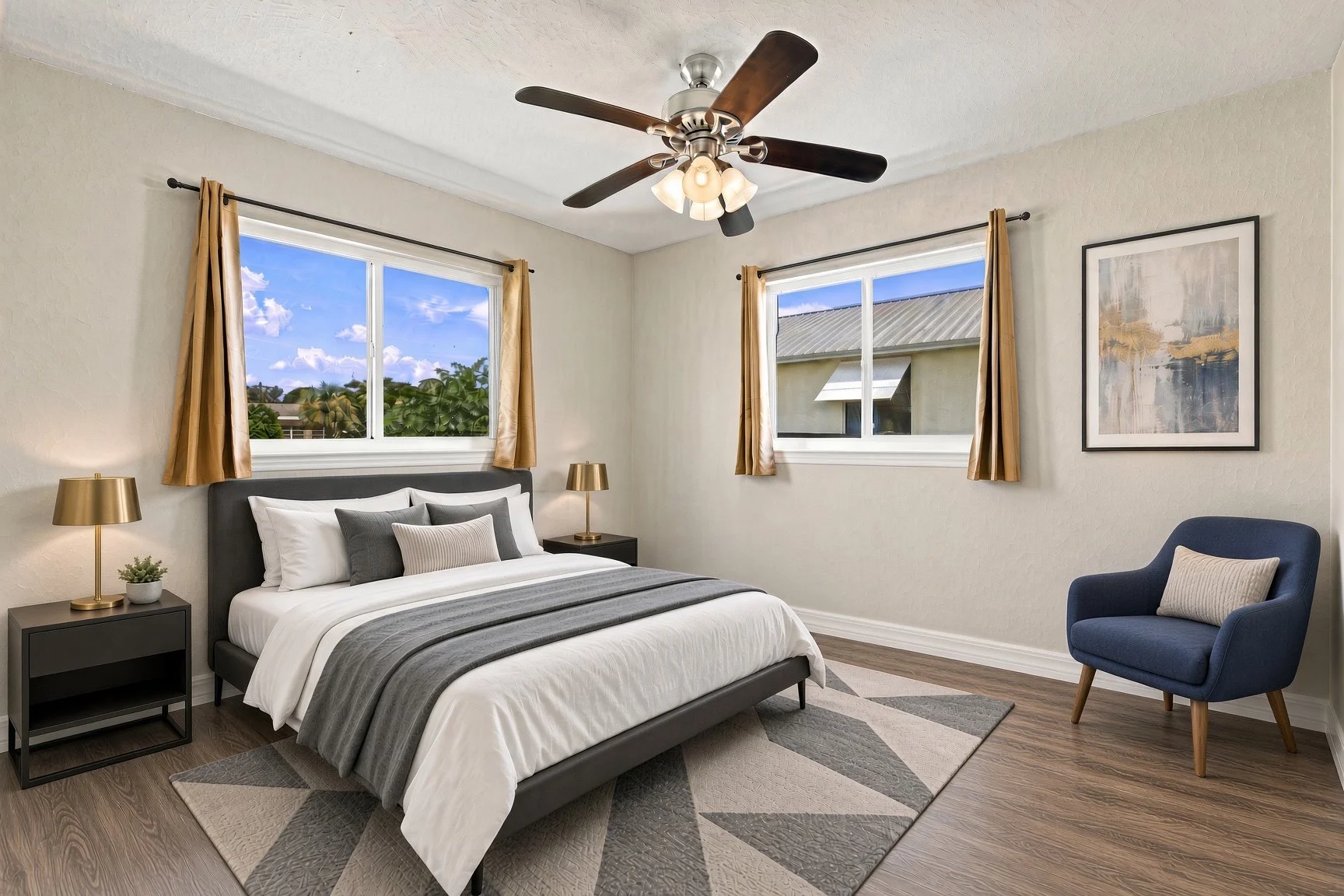 Bedroom with ceiling fan, gray bedding and a blue armchair