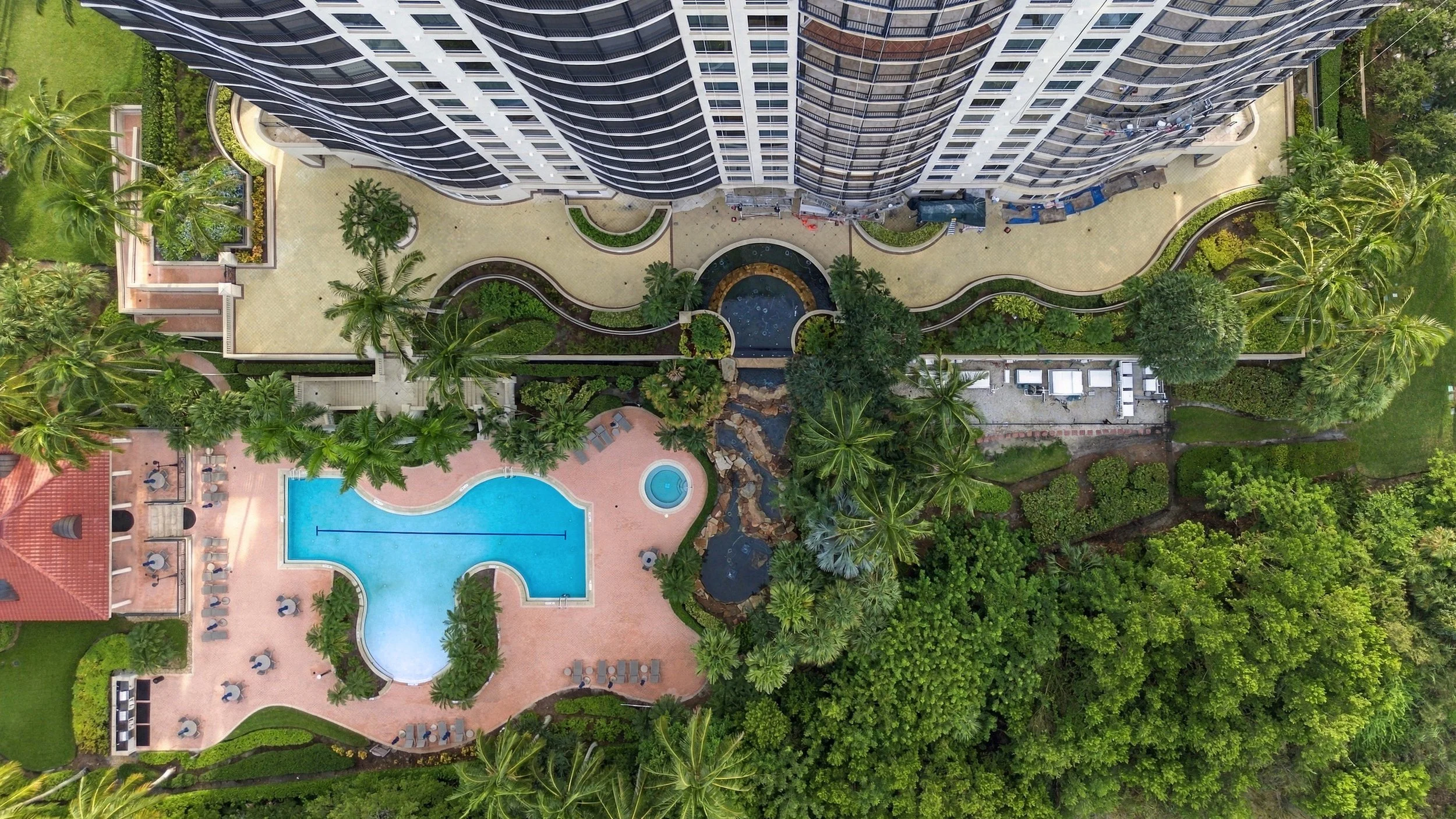 Aerial drone view of a resort-style pool surrounded by trees
