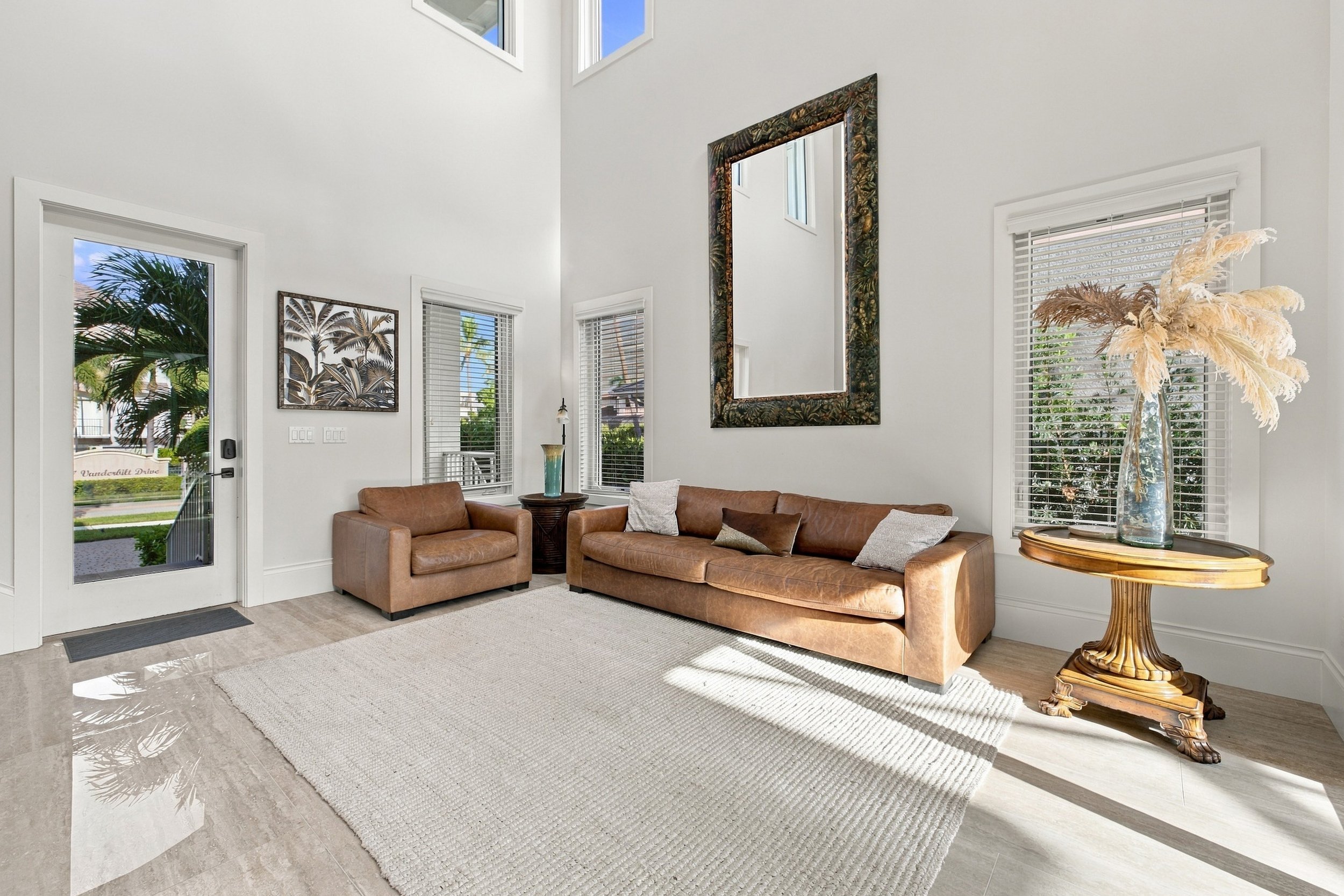 Living room with leather sofas, tall windows and a large wall mirror