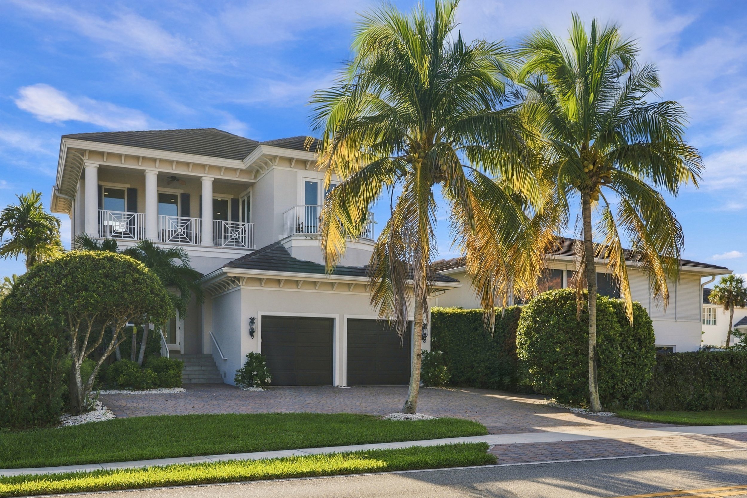 Two-story home with palm trees and a two-car garage, the kind of property we photograph in Naples