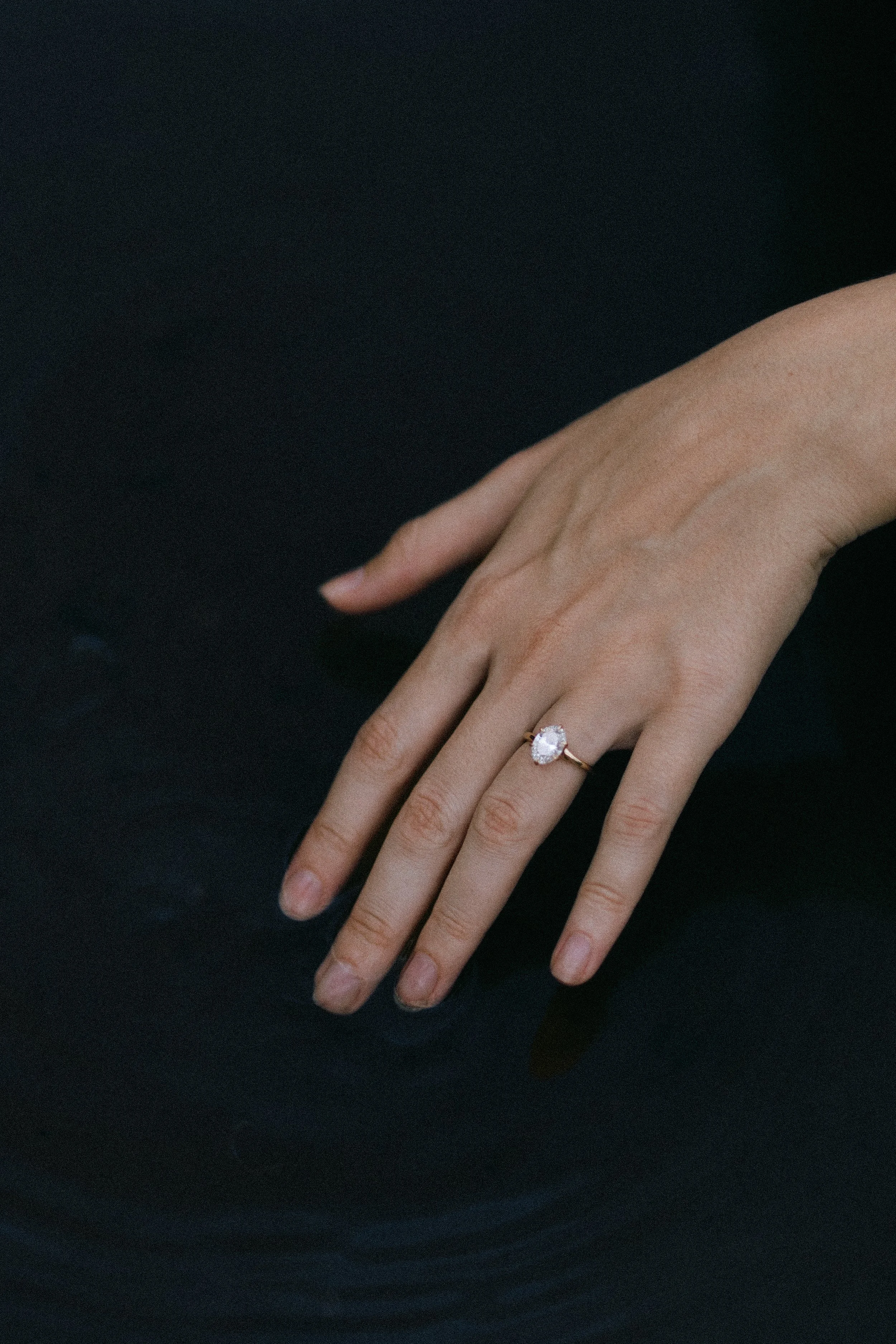 Hand with a diamond ring above dark water surface