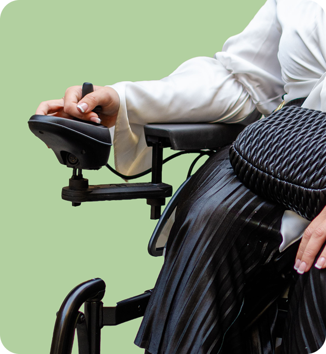Close-up of a person in a white shirt operating a motorized wheelchair with a green background.