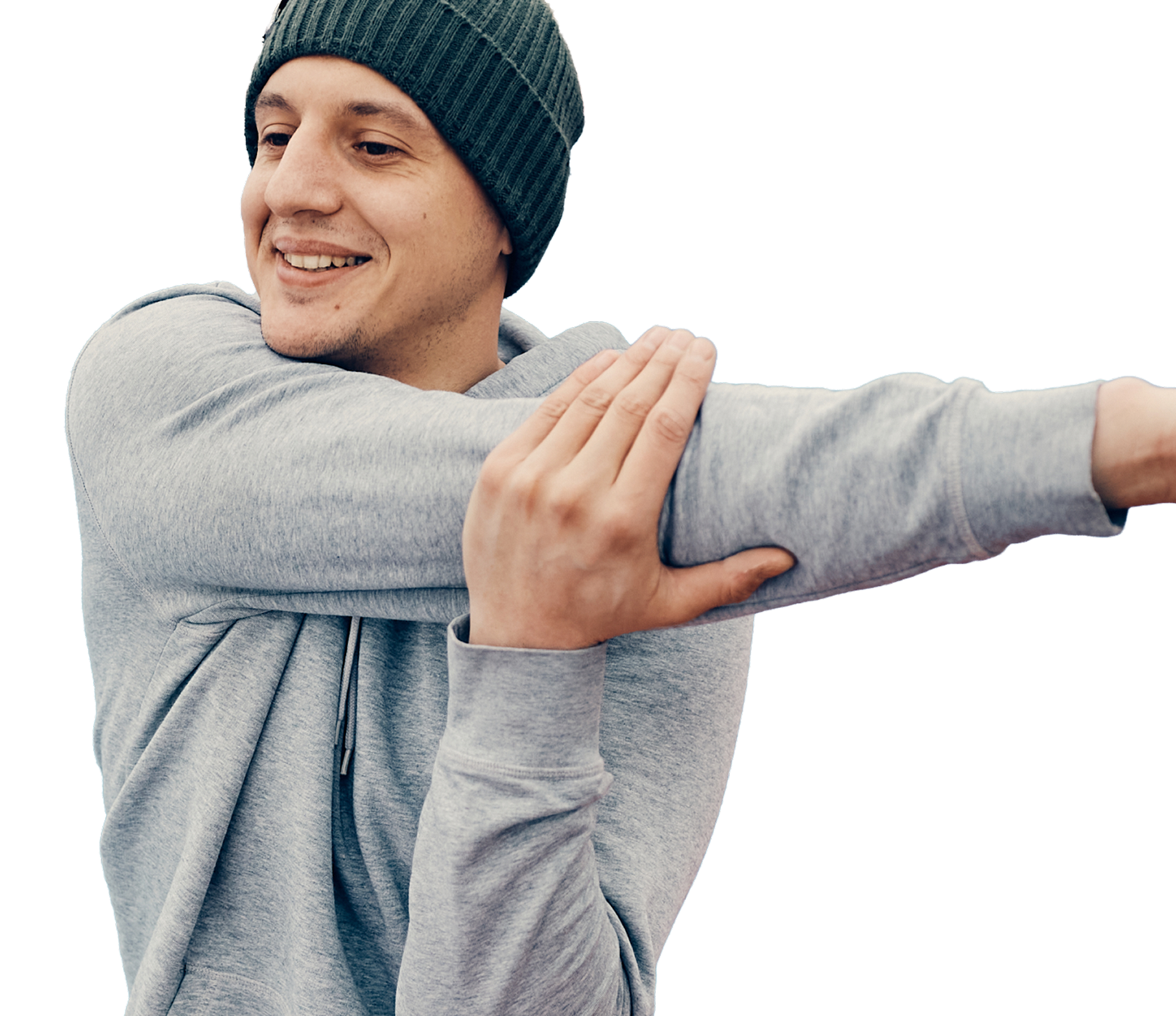 Young man stretching his arms, smiling, wearing a gray hoodie and a beanie