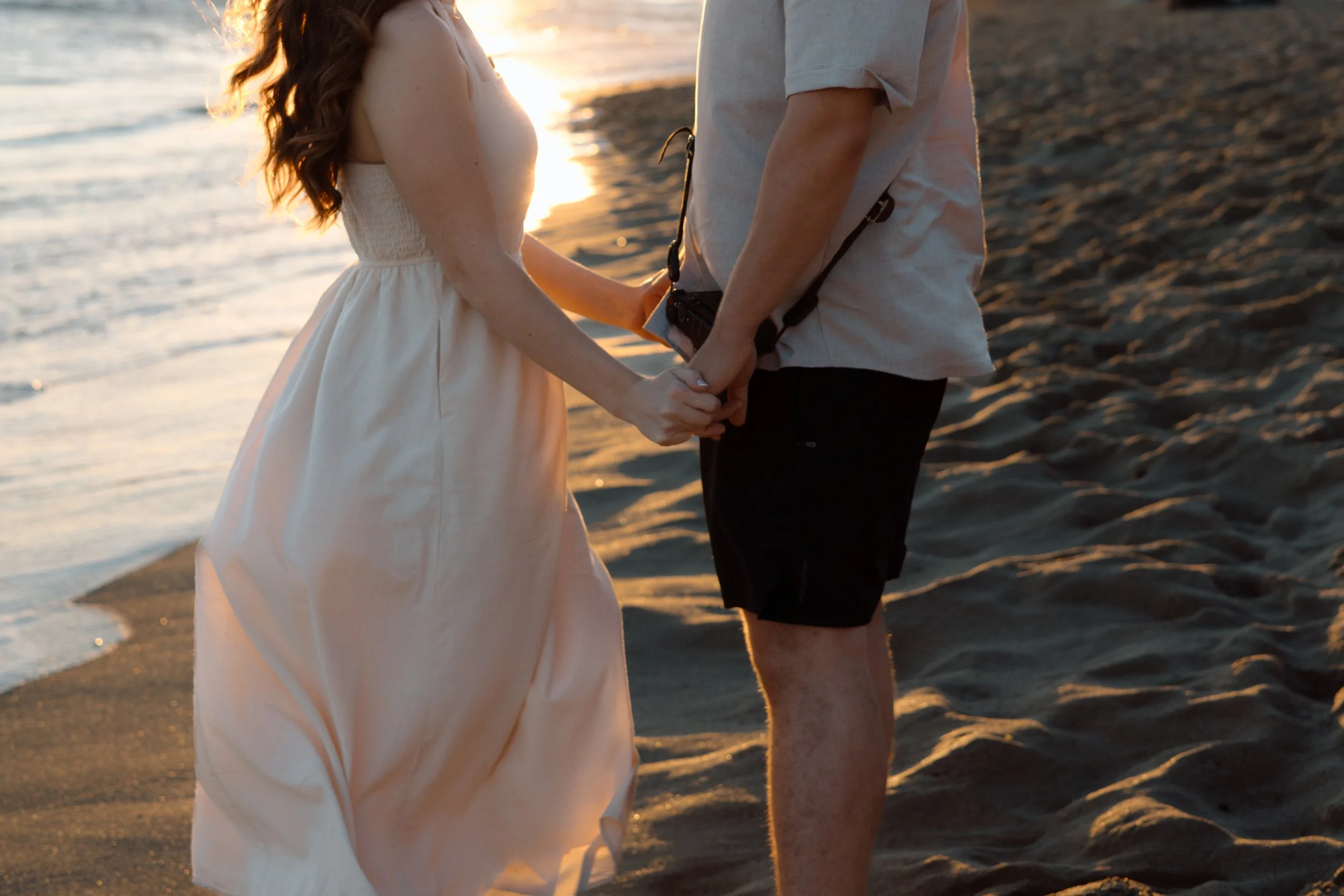 Couple walking hand in hand along the beach at sunset, photographed by their Algarve couples photographer